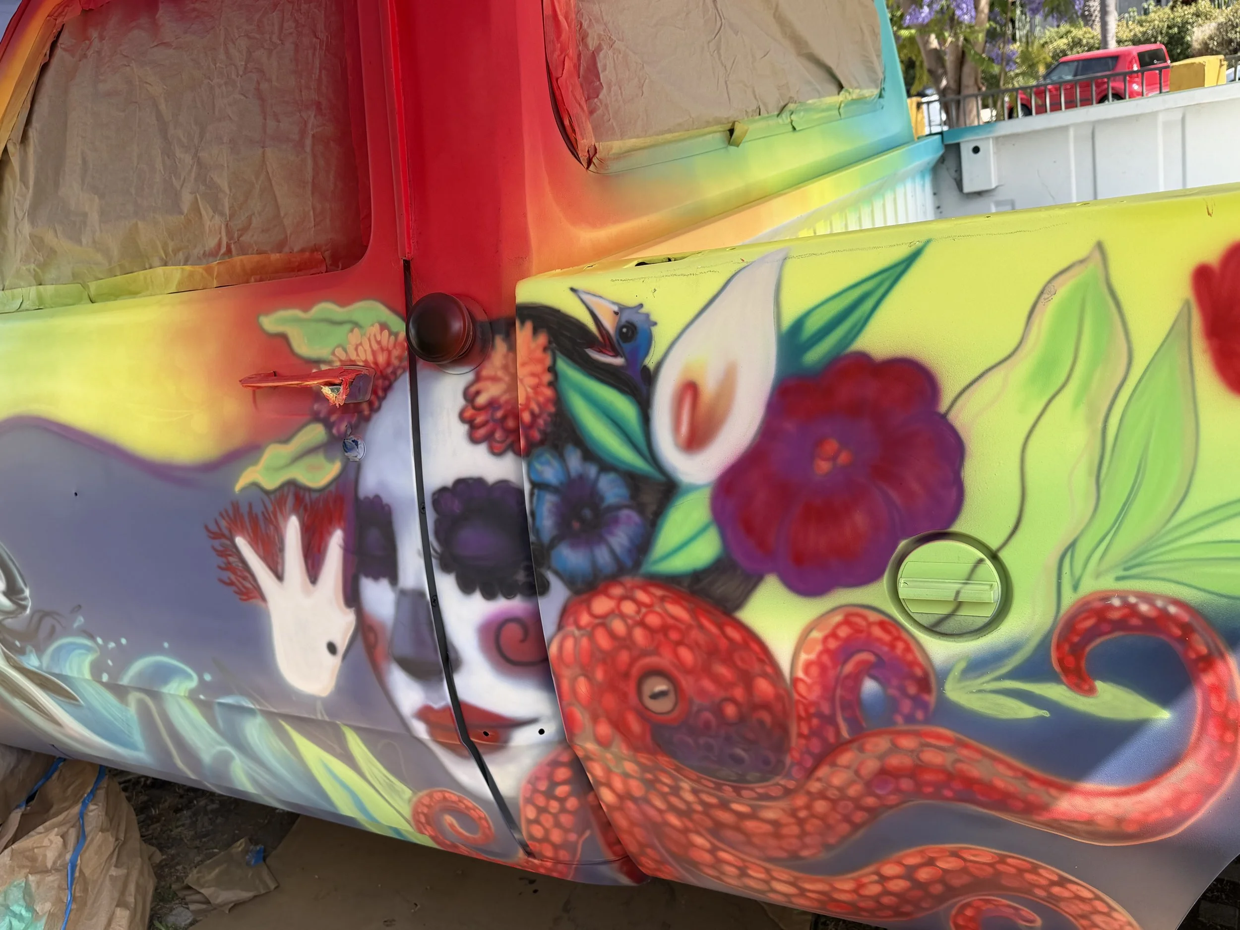 Mar de Flores artwork in progress featuring an octopus and flowers painted on the side of a vintage Dodge truck.