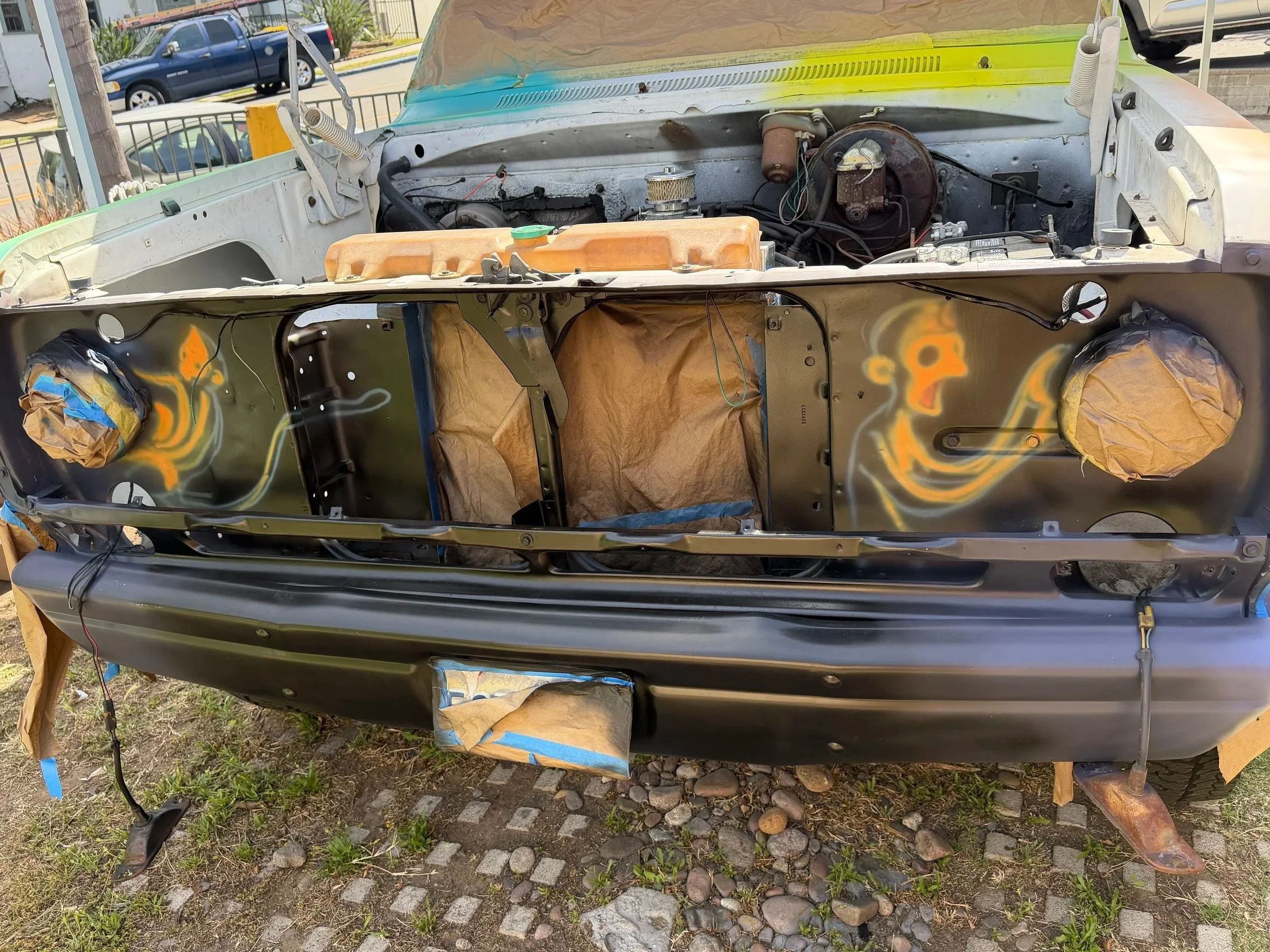 Front grille artwork in progress featuring La Familia Huesos characters painted inside a vintage Dodge truck grille.