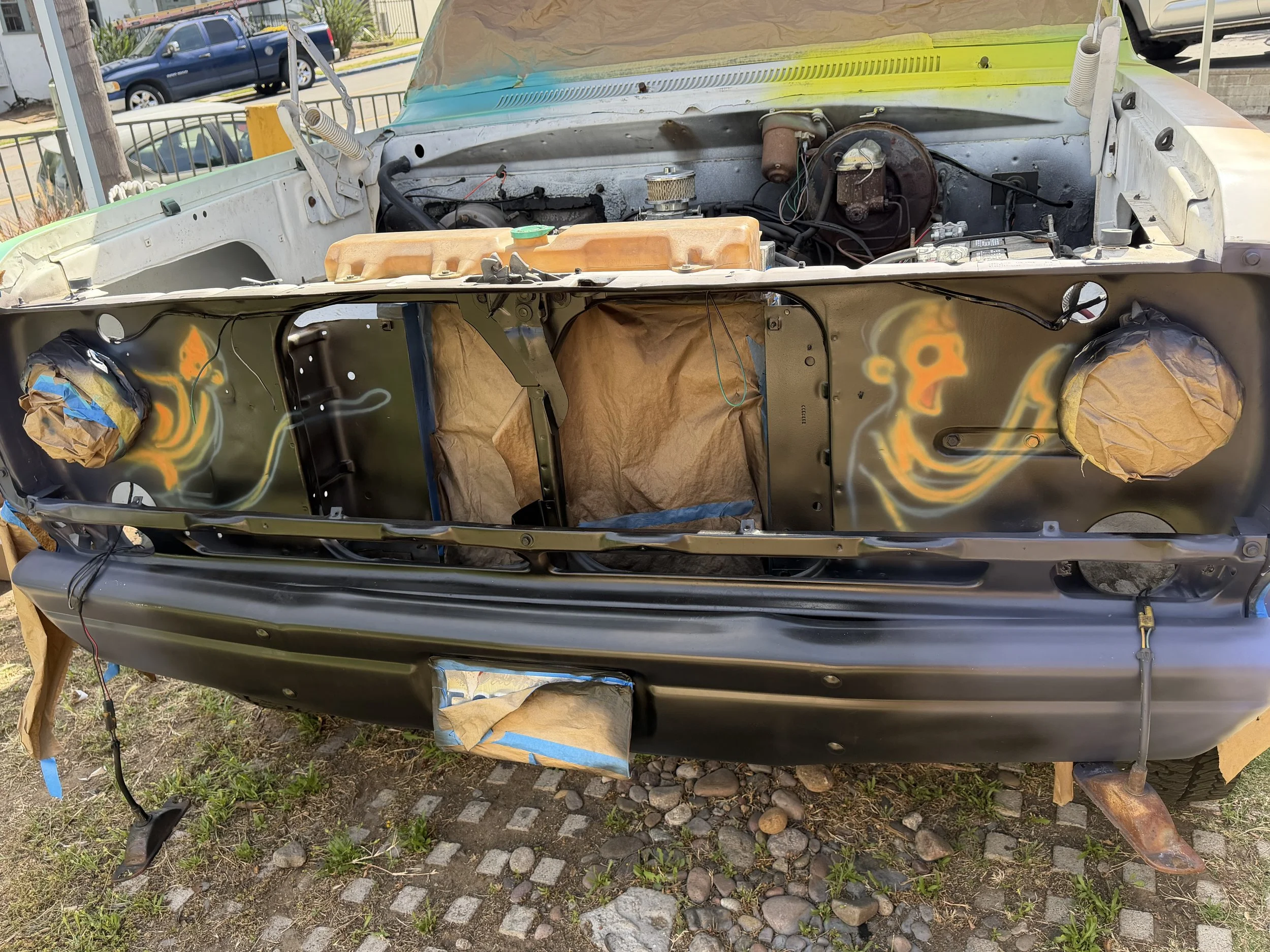 Front grille artwork in progress featuring La Familia Huesos characters painted inside a vintage Dodge truck grille.