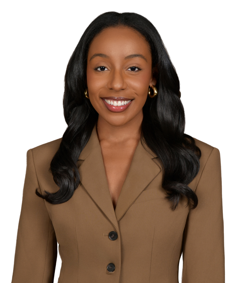 A woman with long black hair, smiling, wearing a tan blazer and gold hoop earrings, against a black background.