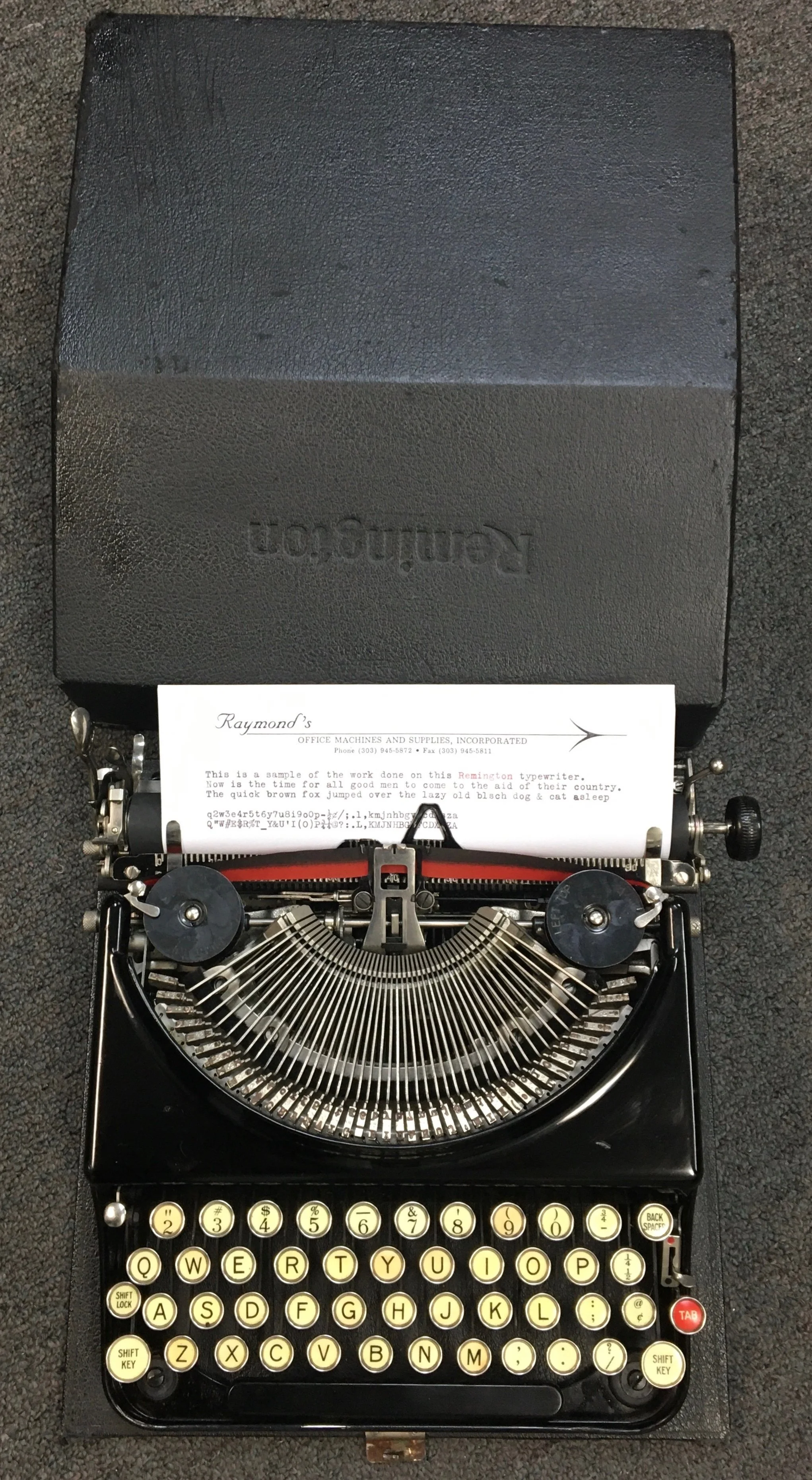 A vintage Remington typewriter with a sheet of paper inserted and typed text, positioned on a dark surface.