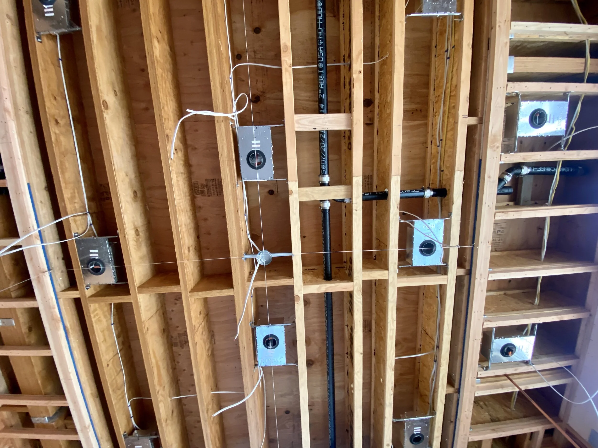 Those silver boxes get first dibs on the space between the joists.  Lines of string are used to get perfect position.  The black plumbing pipe works with whatever space is leftover