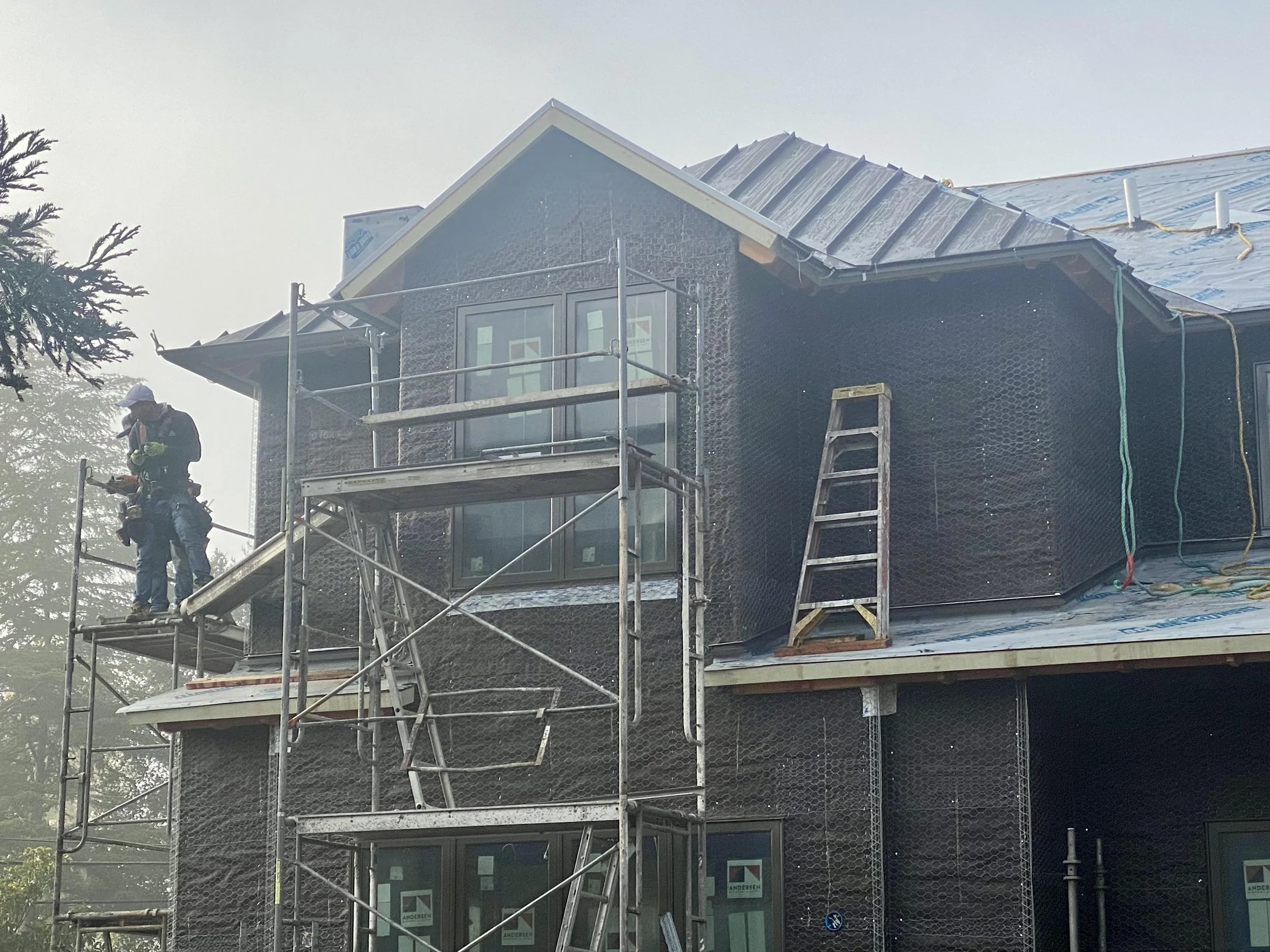 Workers climb scaffolding to apply the stucco layers