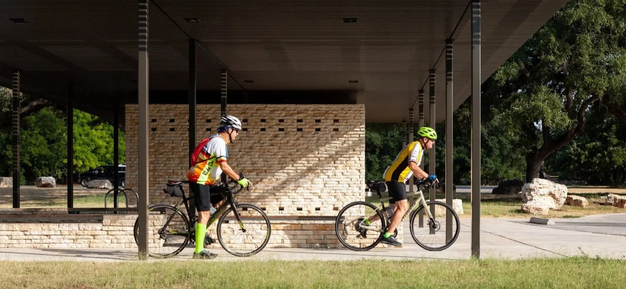 two men riding bikes from a trailhead restroom