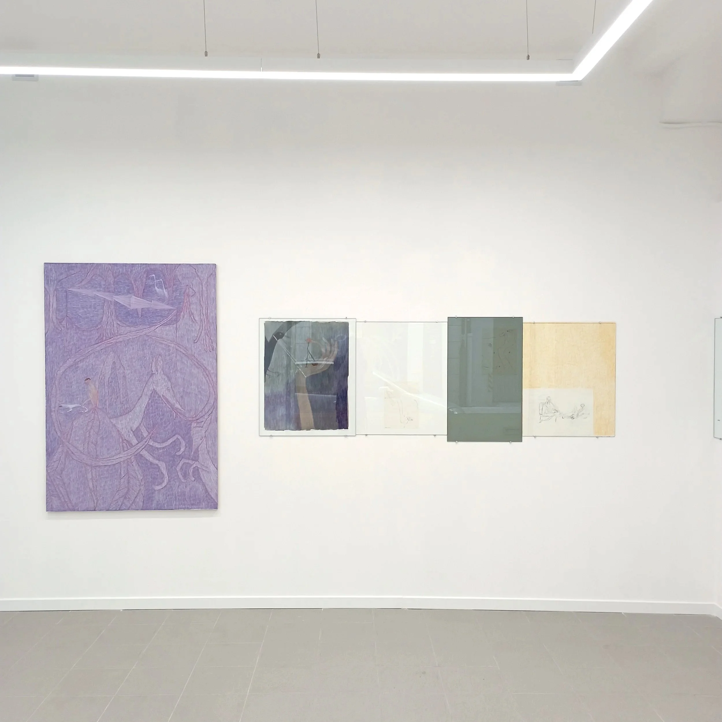 Exposición de obras de arte en una galería con paredes blancas y obras enmarcadas de diferentes tamaños y estilos.