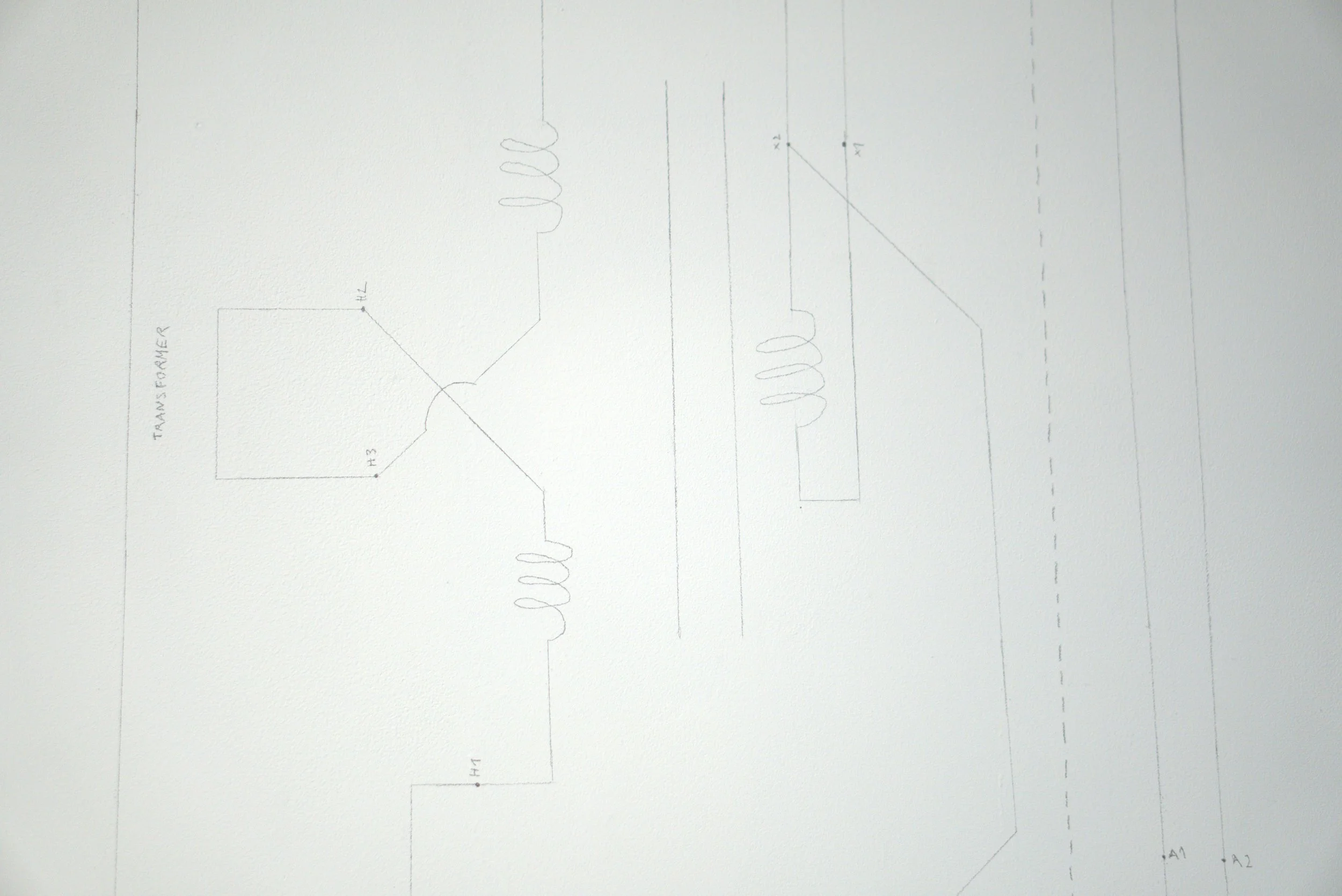 Esquema técnico en papel con componentes electrónicos y conexiones, incluyendo transformador, y bobinas.
