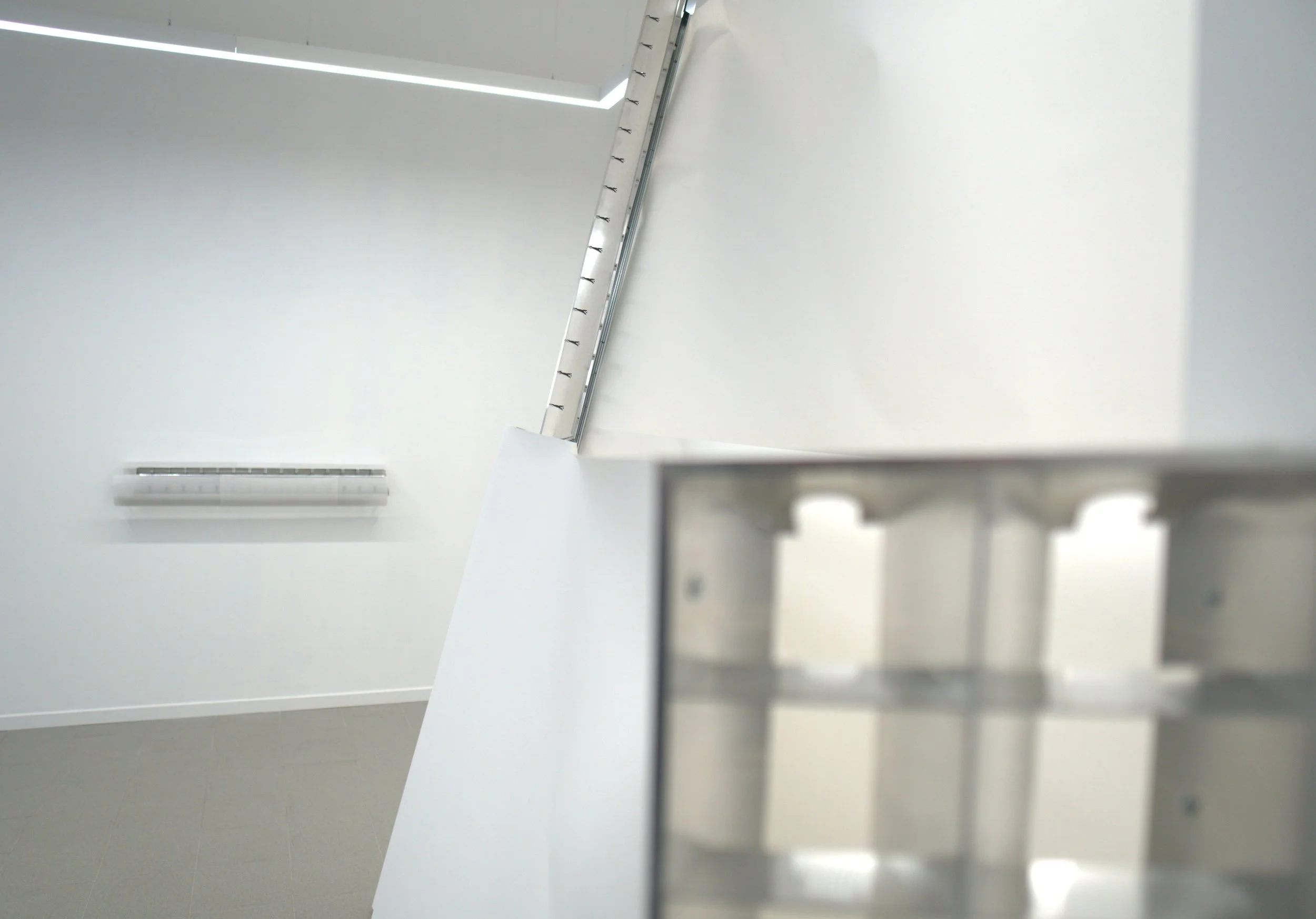 Vista de un espacio interior moderno con paredes blancas y techo con lineas de luz LED, con un aire minimalista.