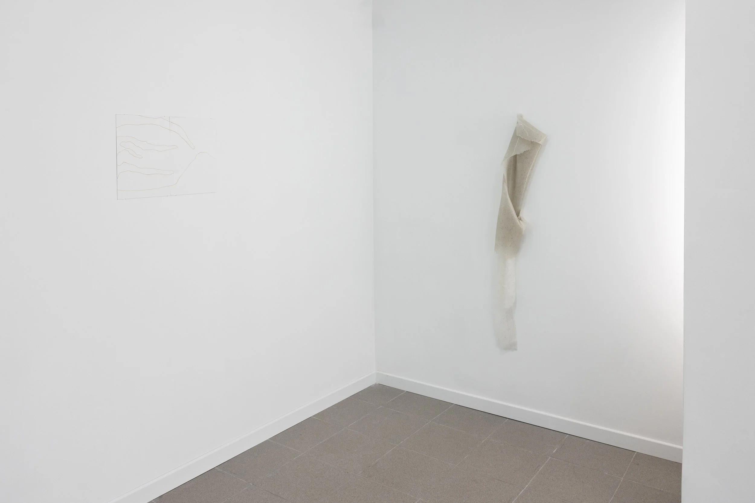 Artefacto de cerámica con forma de mano en una galería de arte, con fondo de paredes blancas y suelo de baldosas grises.