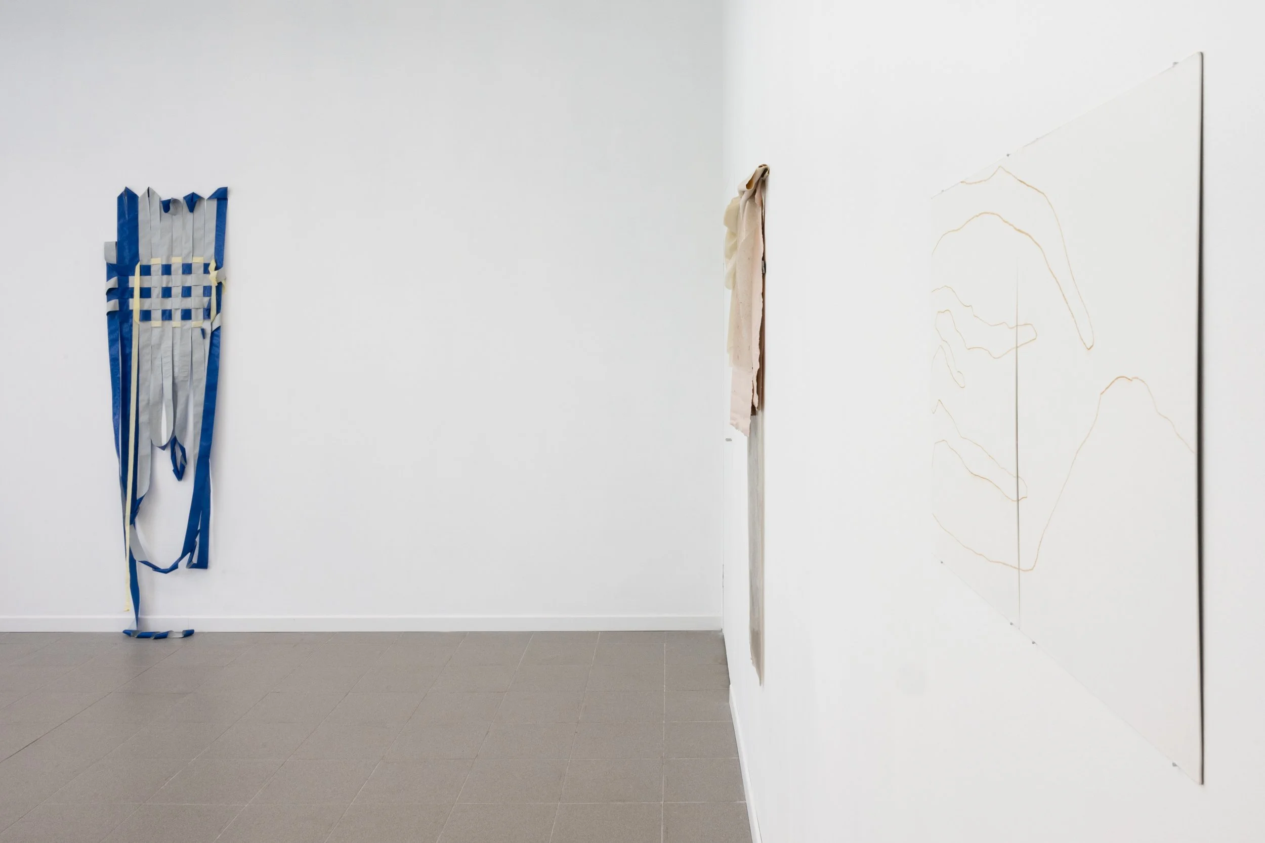 Instalación artística con objetos tejidos y hojas de papel en blanco en una galería