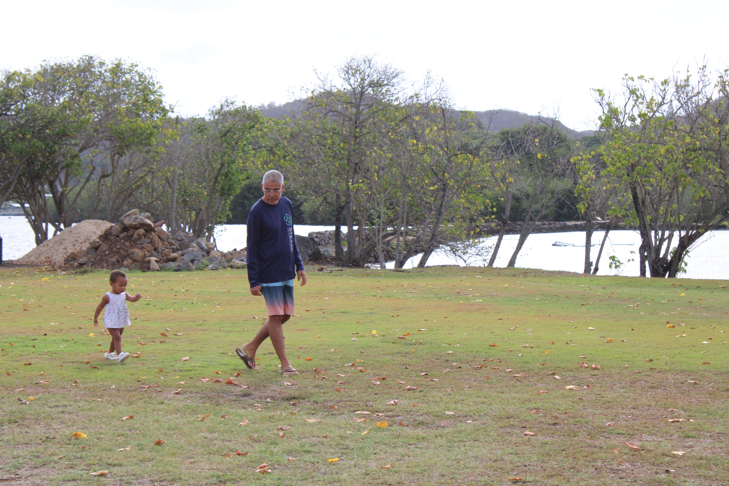 A father and daughter walk at a pond.