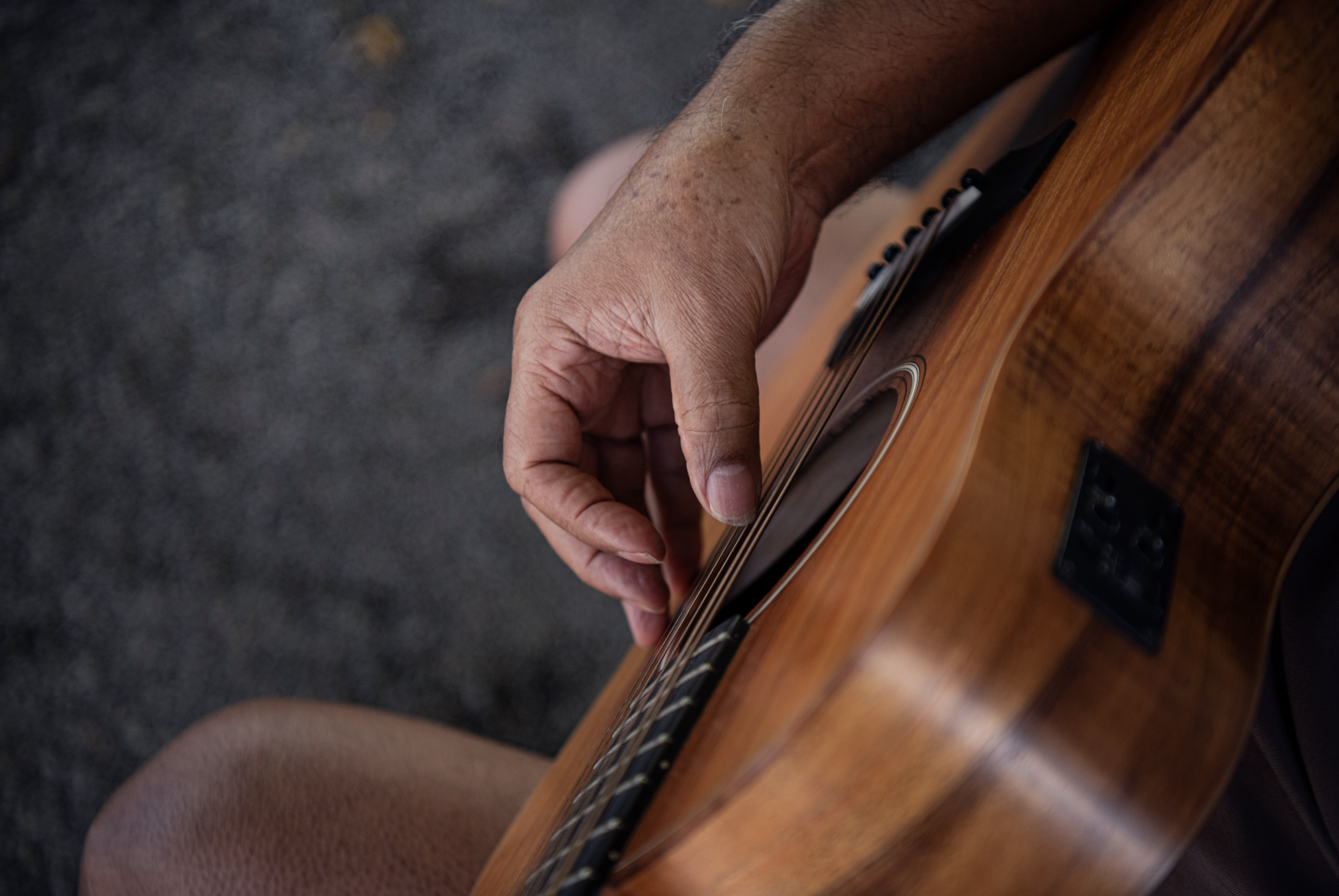 A person playing an acoustic guitar, focusing on their left hand on the fretboard.