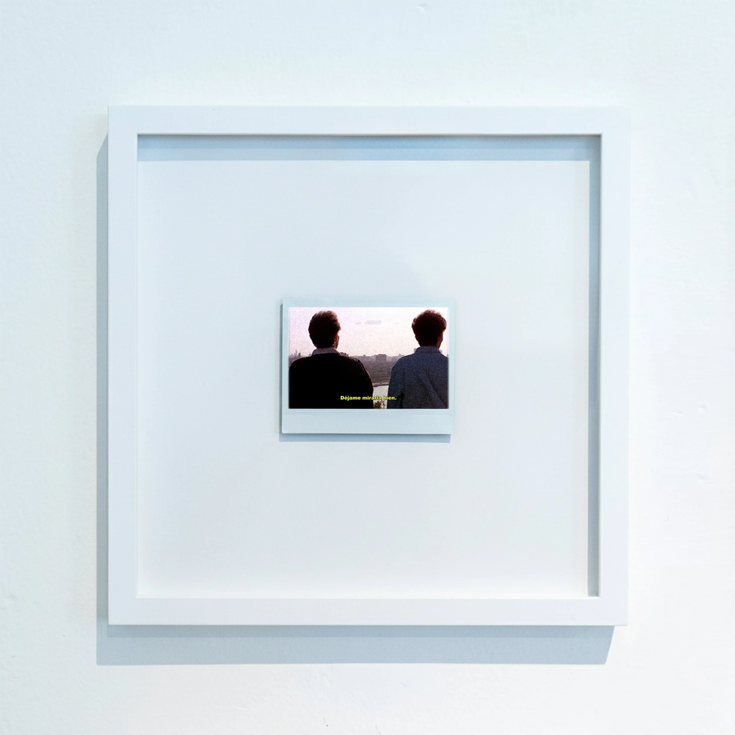 Cuadro que muestra a dos hombres viendo una pantalla en una galería de arte con paredes blancas.
