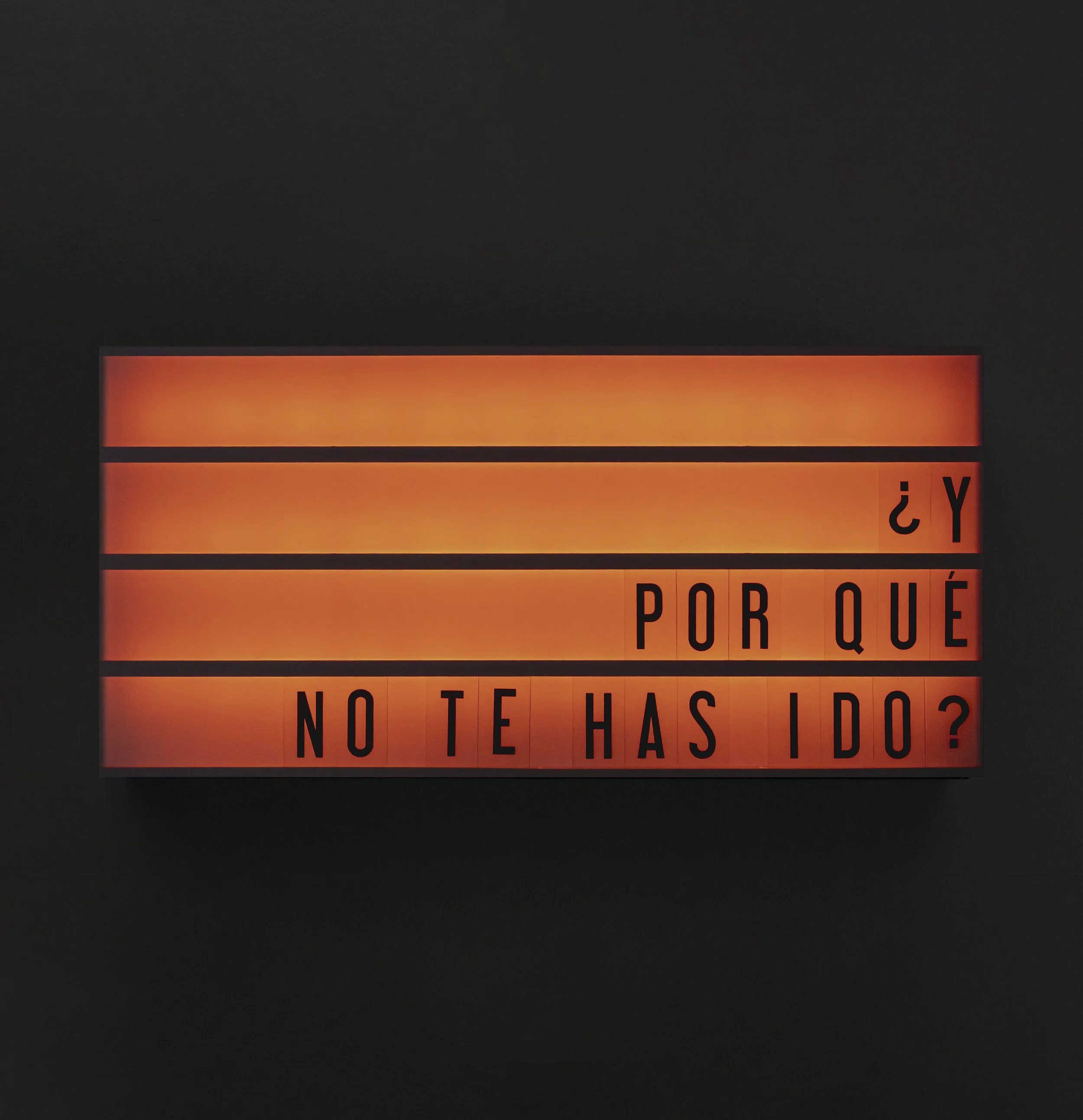 cartel con letras en color naranja y negro en fondo oscuro que dice en parte: '¿Y por qué no te has ido?'