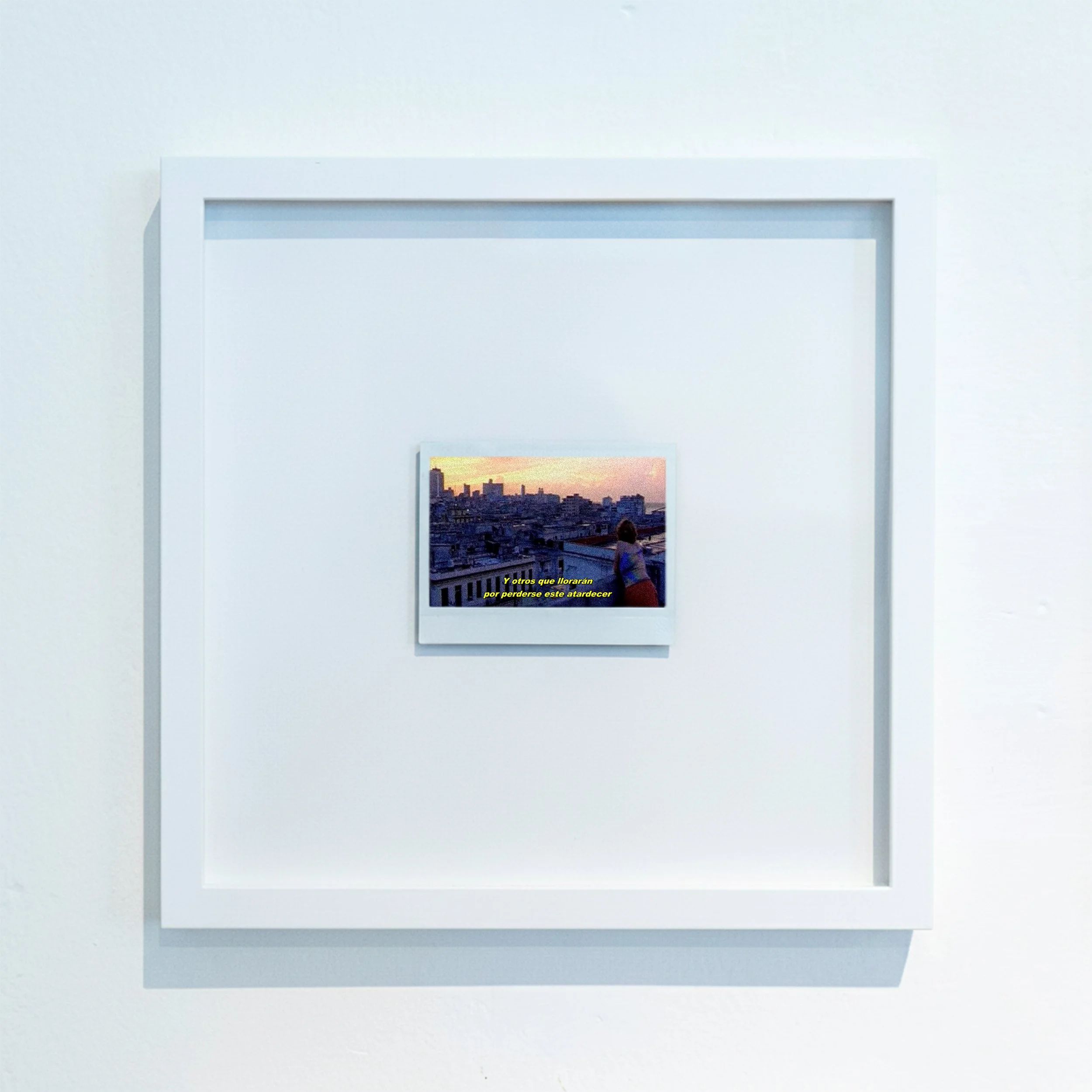 Cuadro con una ciudad al atardecer, enmarcado en una pared blanca