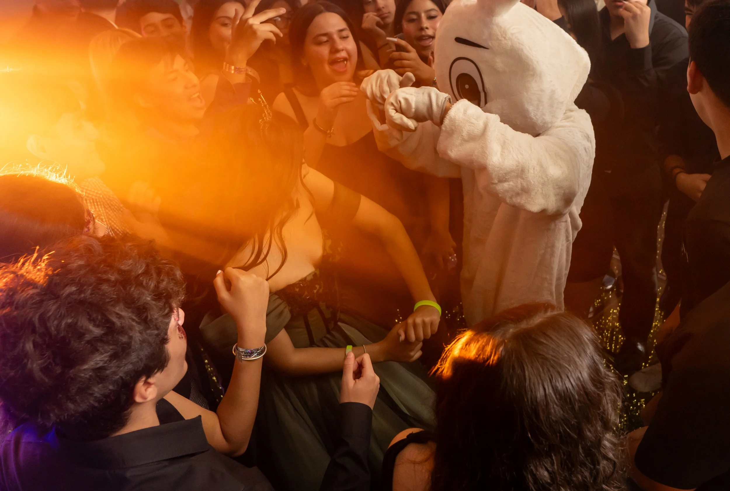 Personaje disfrazado de Olaf, el muñeco de nieve de Frozen, interactuando con un grupo de jóvenes en un evento, rodeados de múltiples espectadores y luces cálidas.