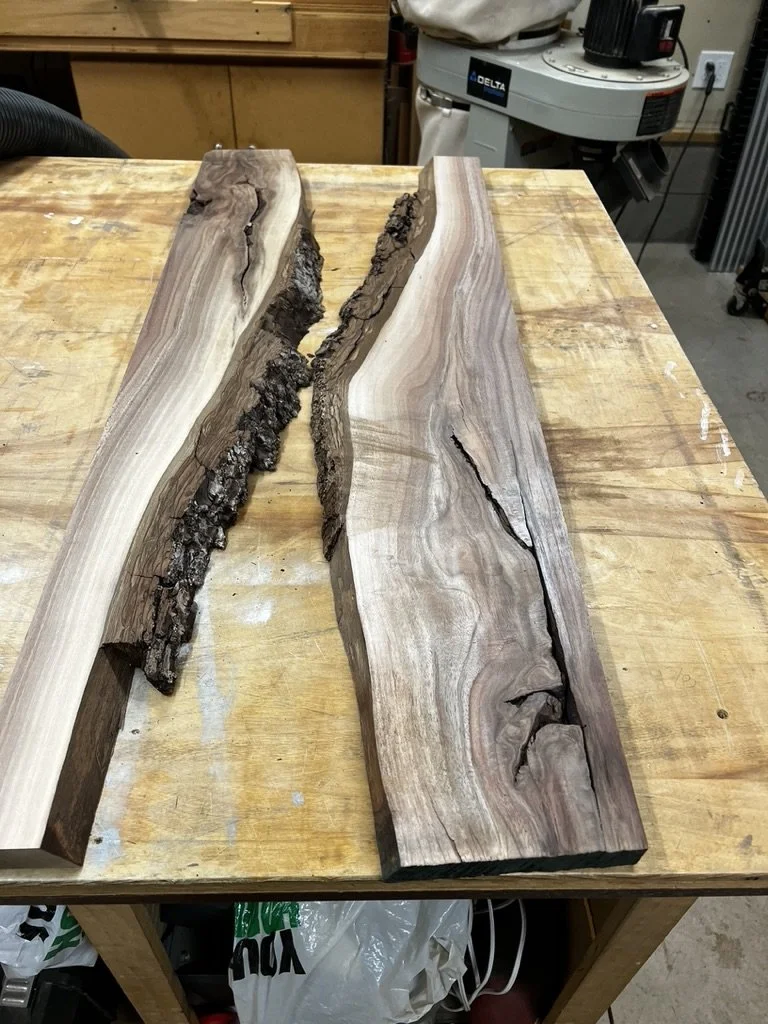 Two pieces of wood with natural bark edges on a woodworking workbench in a workshop.