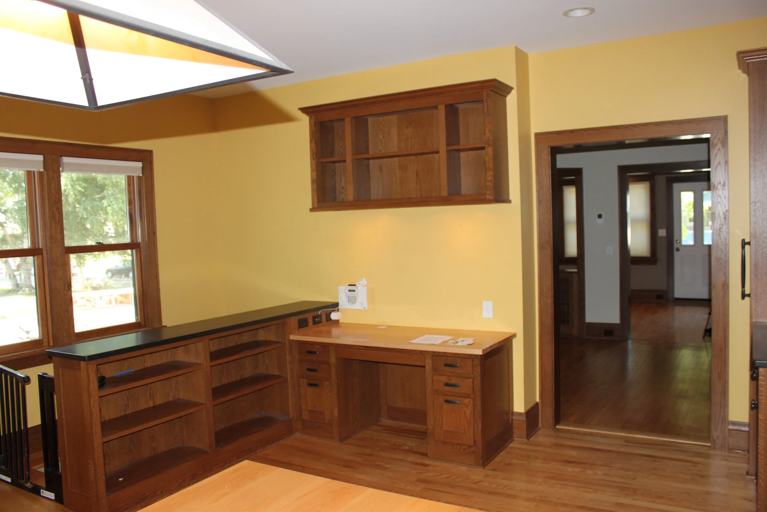 Interior of a room with yellow walls, wooden cabinetry, and a window showing a view of trees outside.