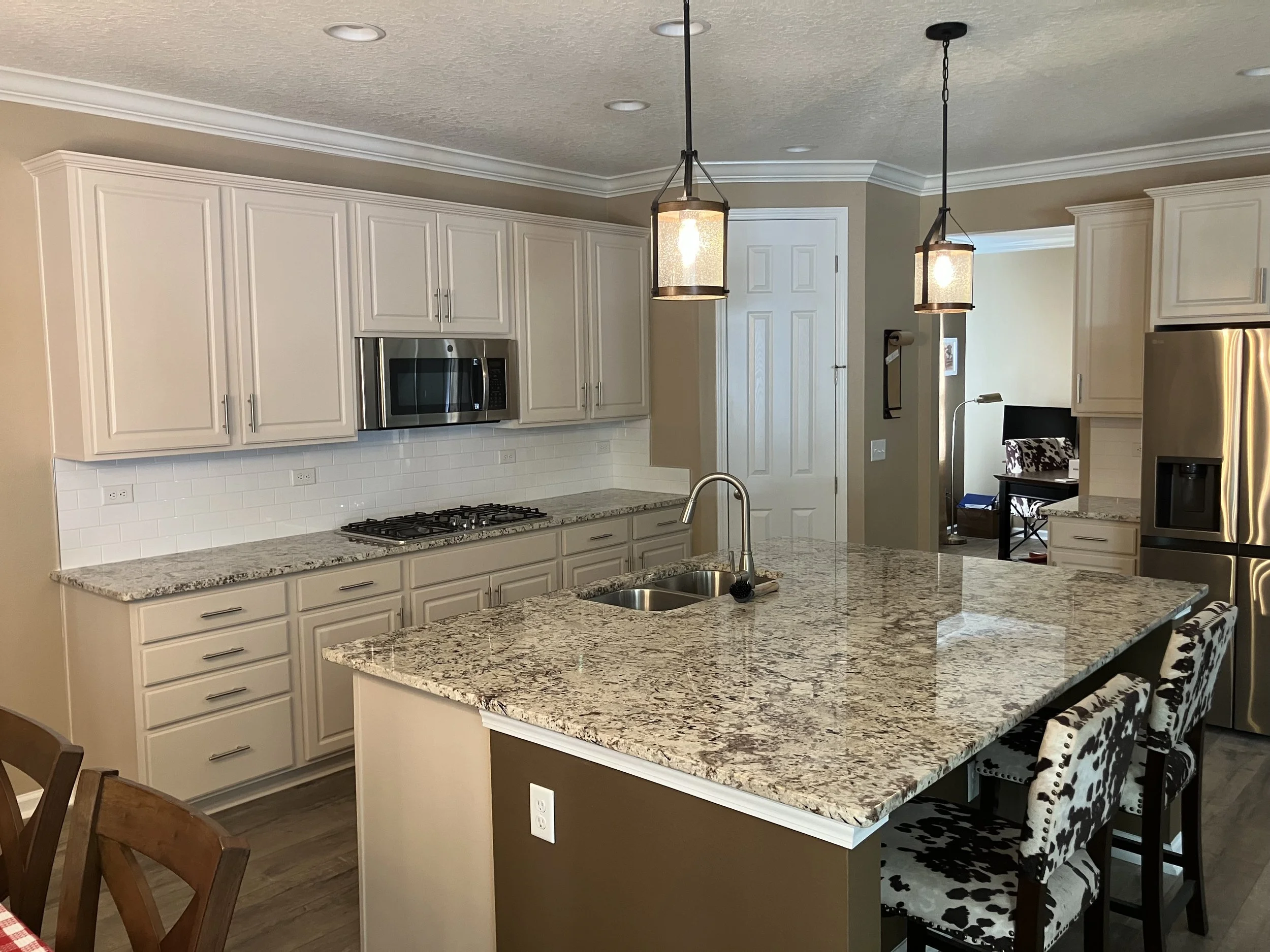 Warm white kitchen cabinetry and island with stone countertops