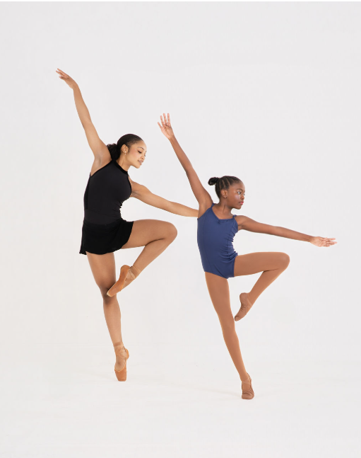 Two young ballet dancers practicing dance moves against a plain white background, one wearing a black leotard and the other in a blue leotard.