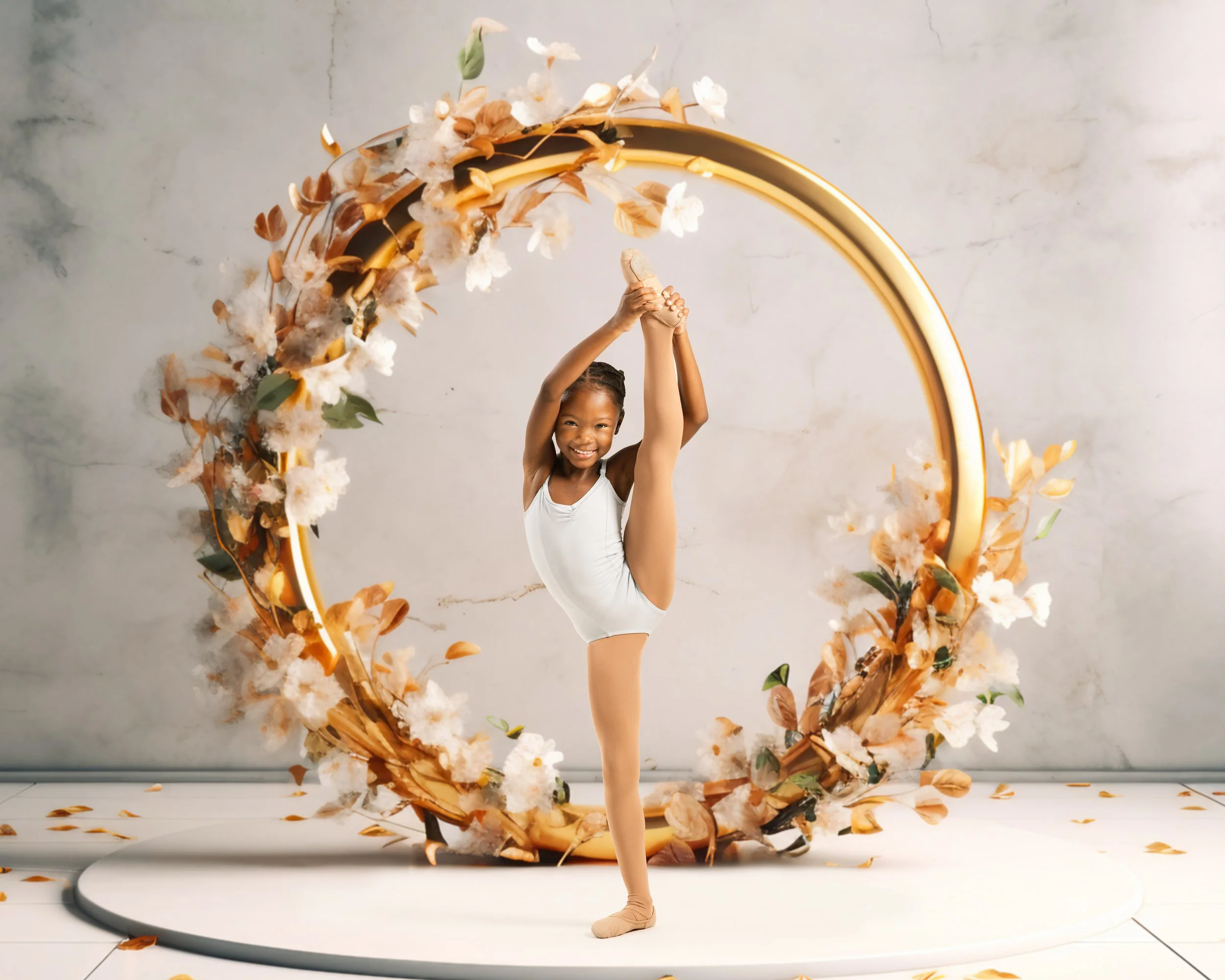 A young girl in a white leotard and beige dance shoes performing a standing split pose, holding her raised leg with both hands, smiling, in front of a decorative gold circular floral frame with white and beige flowers and leaves on a white circular platform.