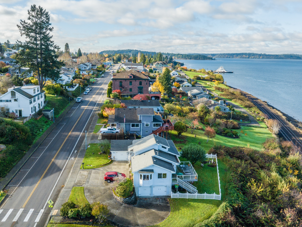 Aerial view of a coastal neighborhood with houses, a waterway, and a bridge, during daytime.