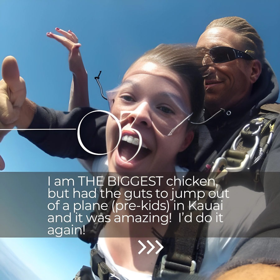 A young girl with a big smile and goggles is mid-air after jumping out of a plane, with an adult man in sunglasses and a harness behind her, against a blue sky background.