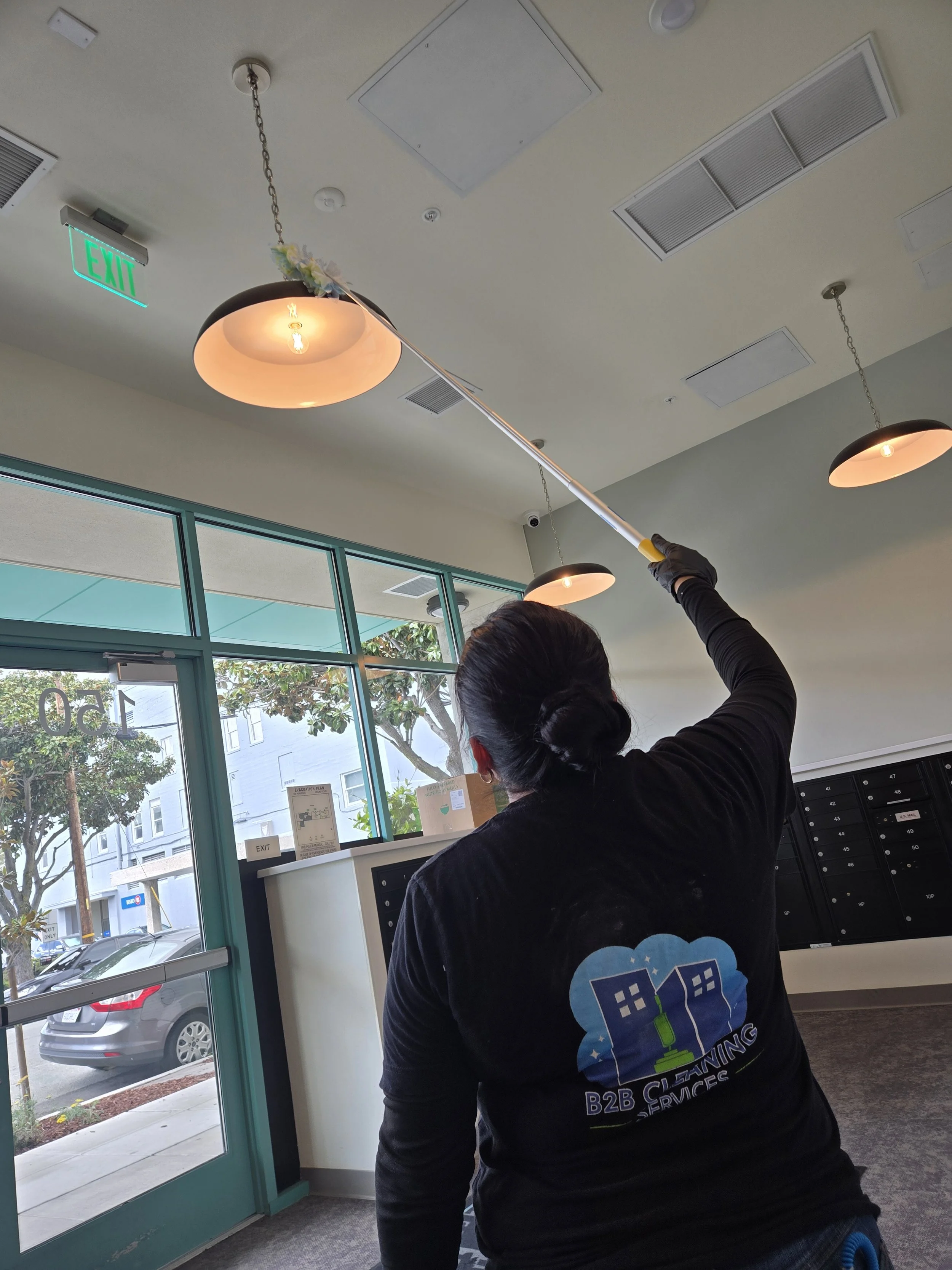 commercial cleaning technician performing high dusting in apartment common area in San Mateo CA