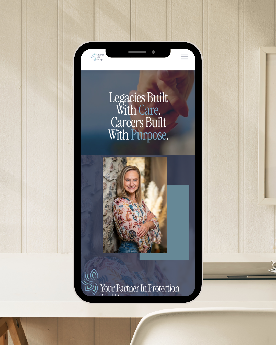 A smartphone displaying a website for Sullivan Life Group, with the tagline "Legacies Built With Care. Careers Built With Purpose." and a photo of a smiling woman standing outdoors against a stone wall.