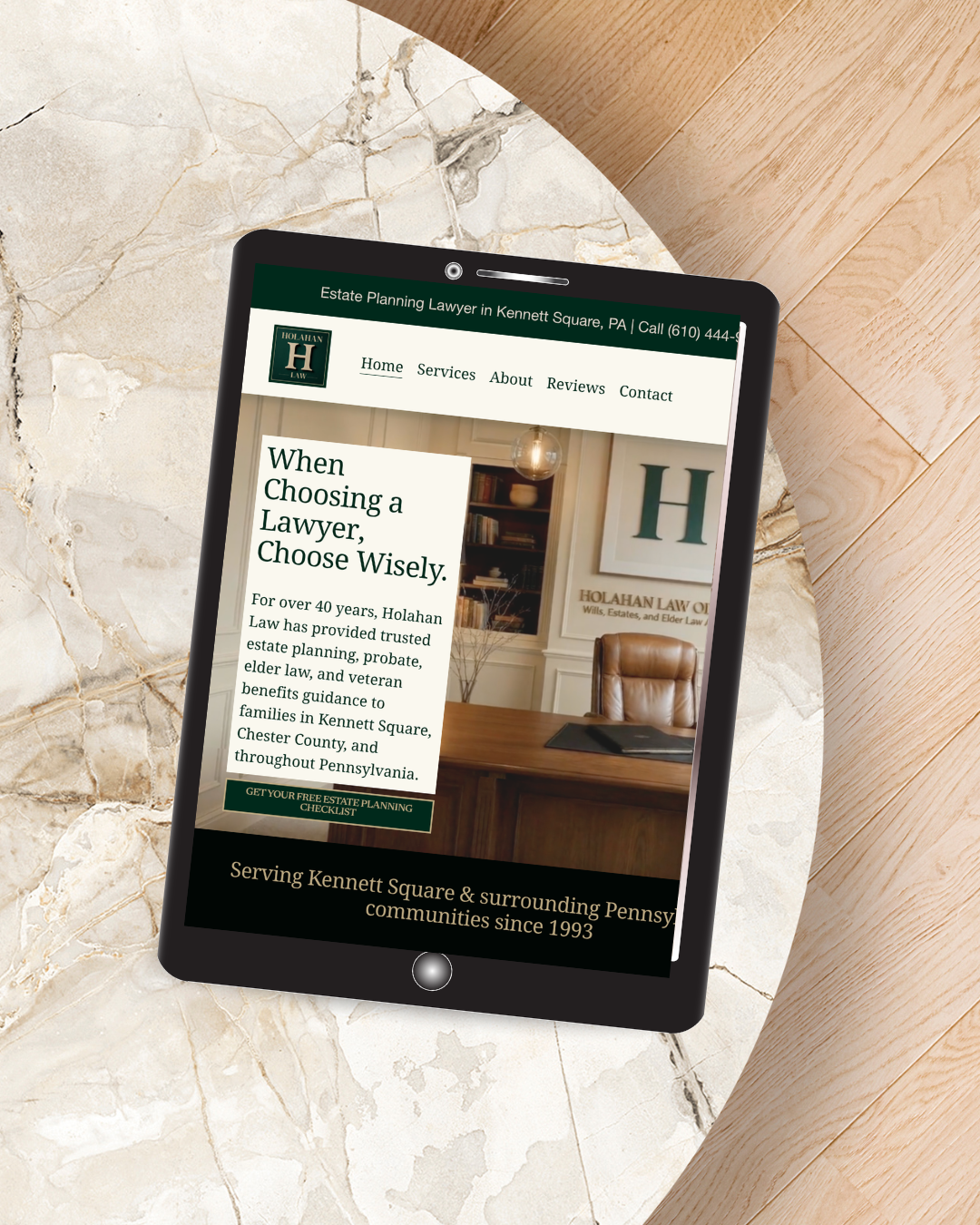 Mobile phone displaying a website for Holahan Law, an estate planning lawyer in Kennett Square, Pennsylvania, with text about choosing a lawyer and a legal office interior background.