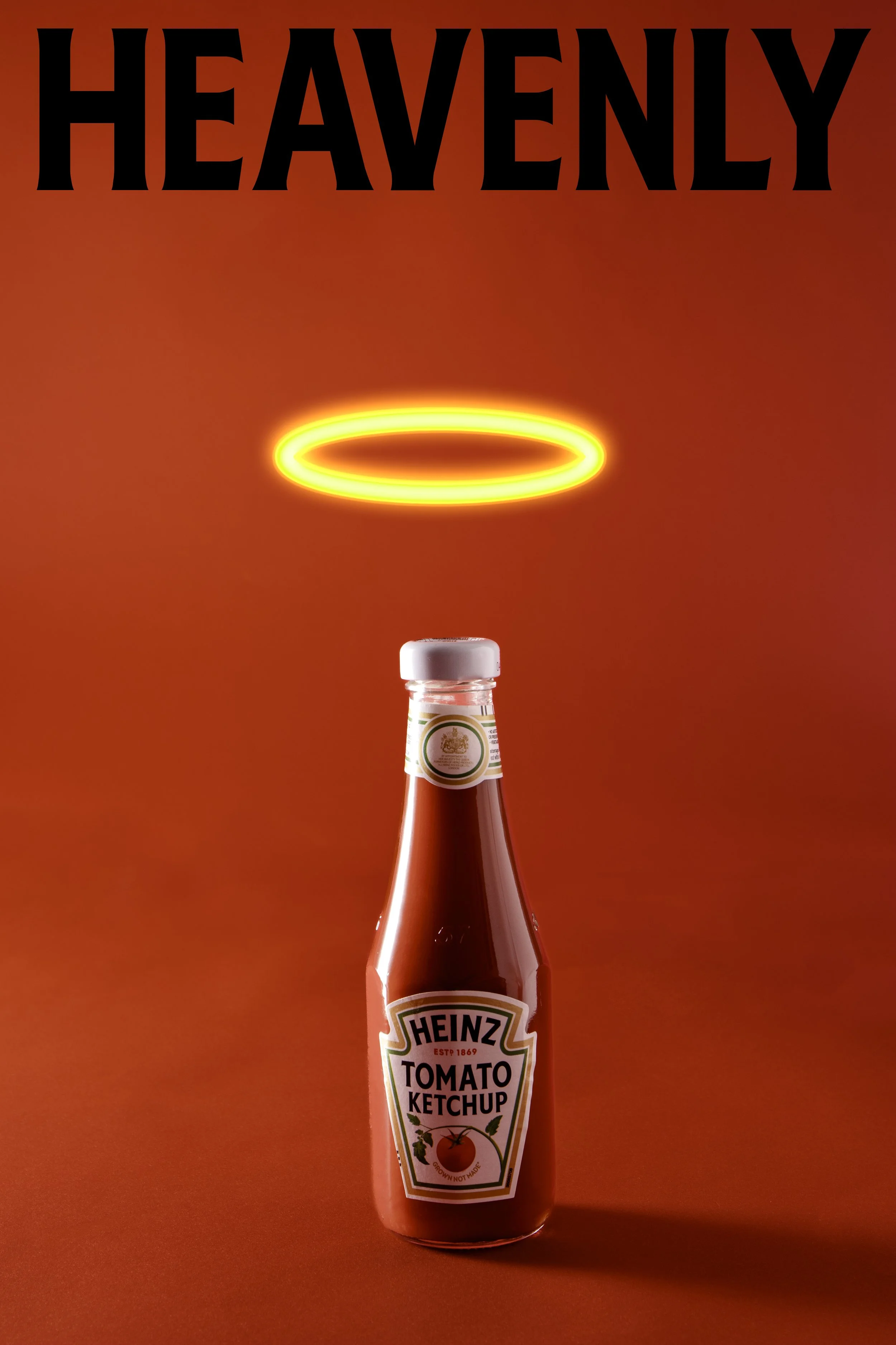 A bottle of Heinz Tomato Ketchup with a glowing halo above it and the word 'HEAVENLY' at the top in large black letters on a red background.