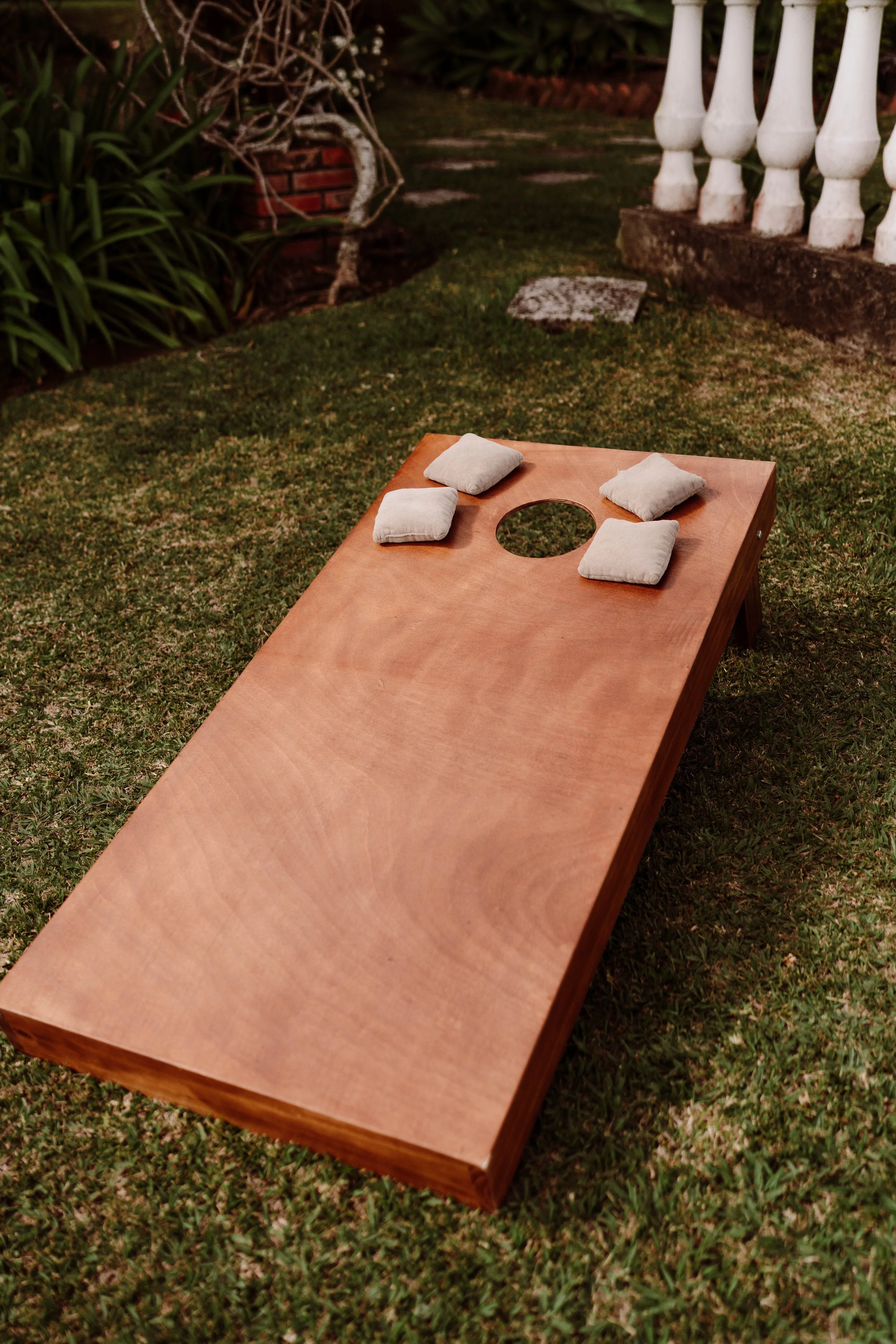 Juego de cornhole al aire libre colocado sobre el césped para que los invitados disfruten durante la celebración de boda.