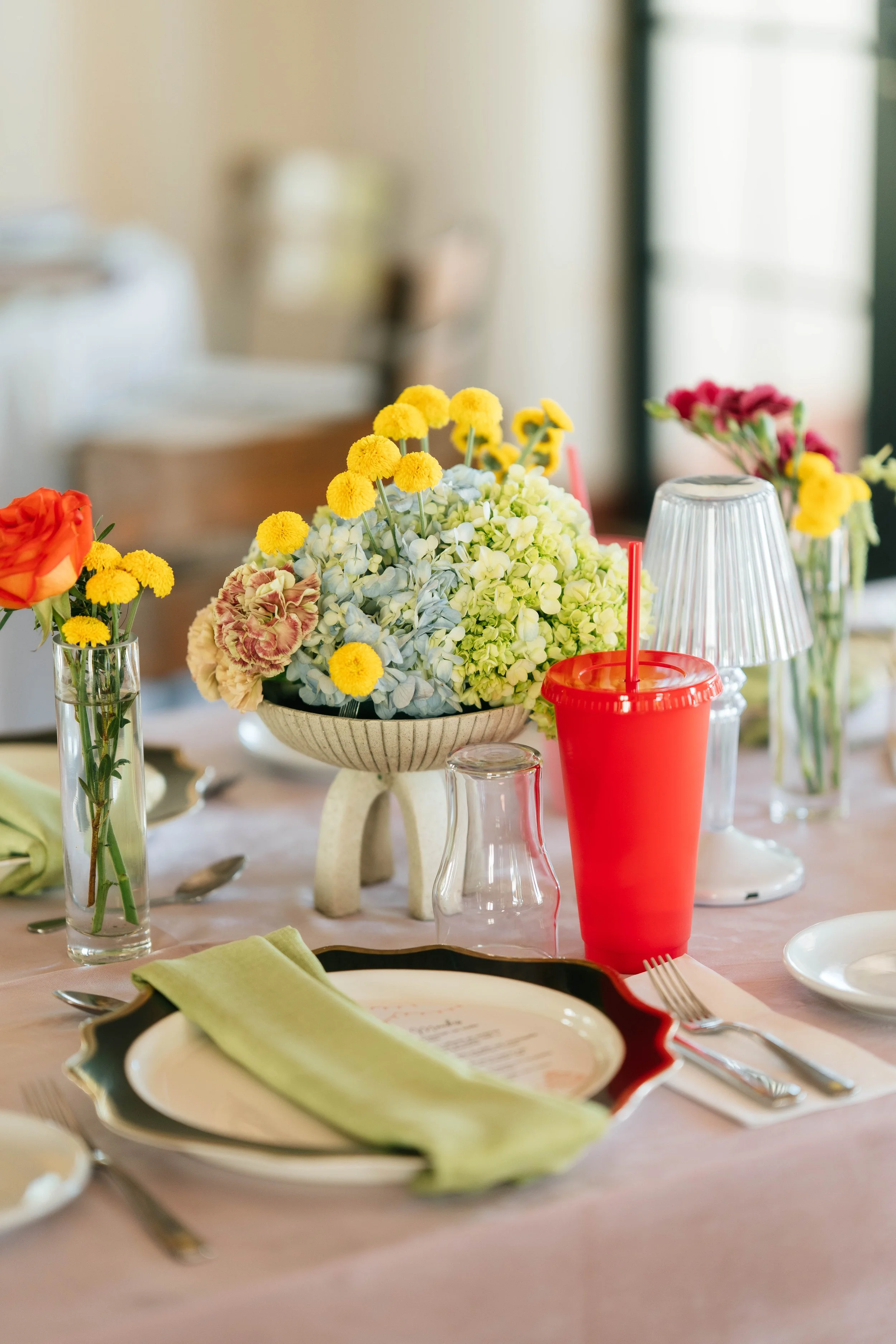 Montaje de mesa con flores, platos, cubiertos, cristalería y detalles de color durante una boda en Costa Rica.
