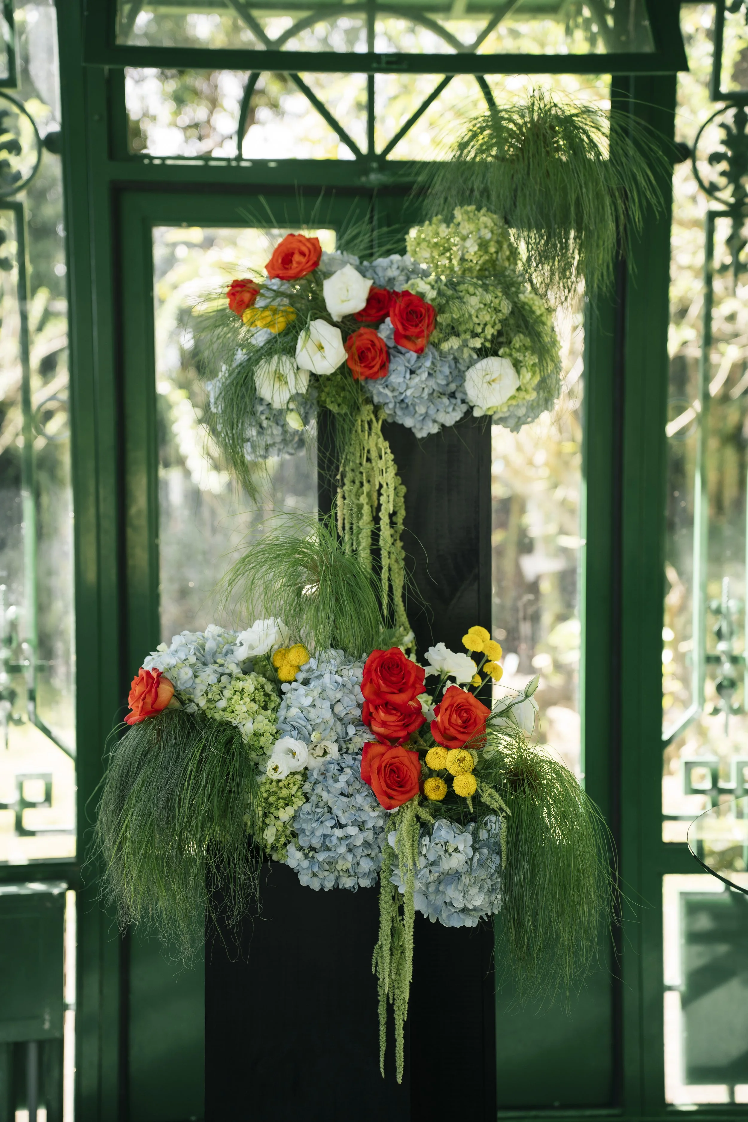 Diseño floral con rosas anaranjadas y blancas, hortensias celestes, flores amarillas y follaje en un espacio interior de boda.