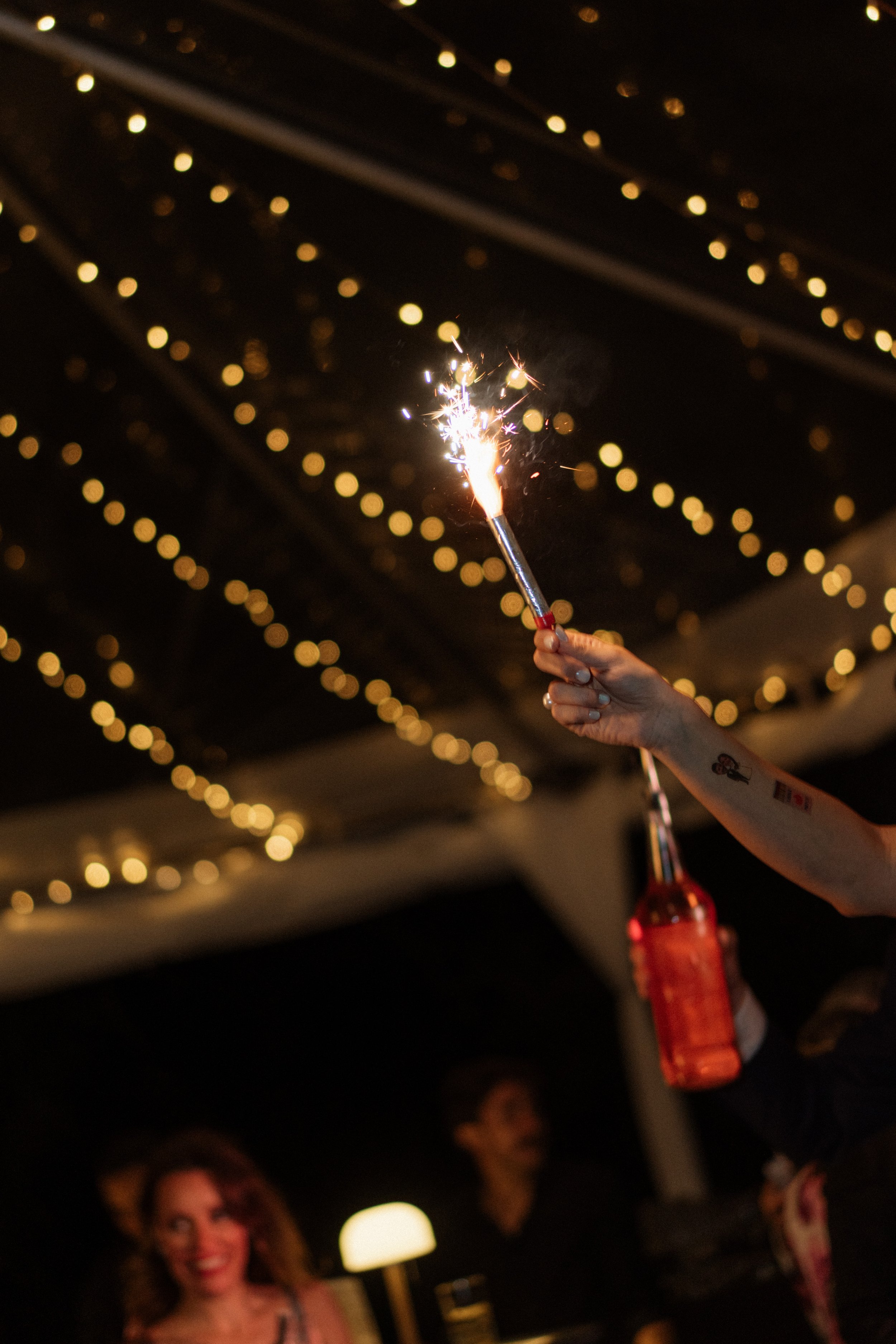 Momento de fiesta con luces de bengala, invitados celebrando y guirnaldas de luces durante una boda en Costa Rica.