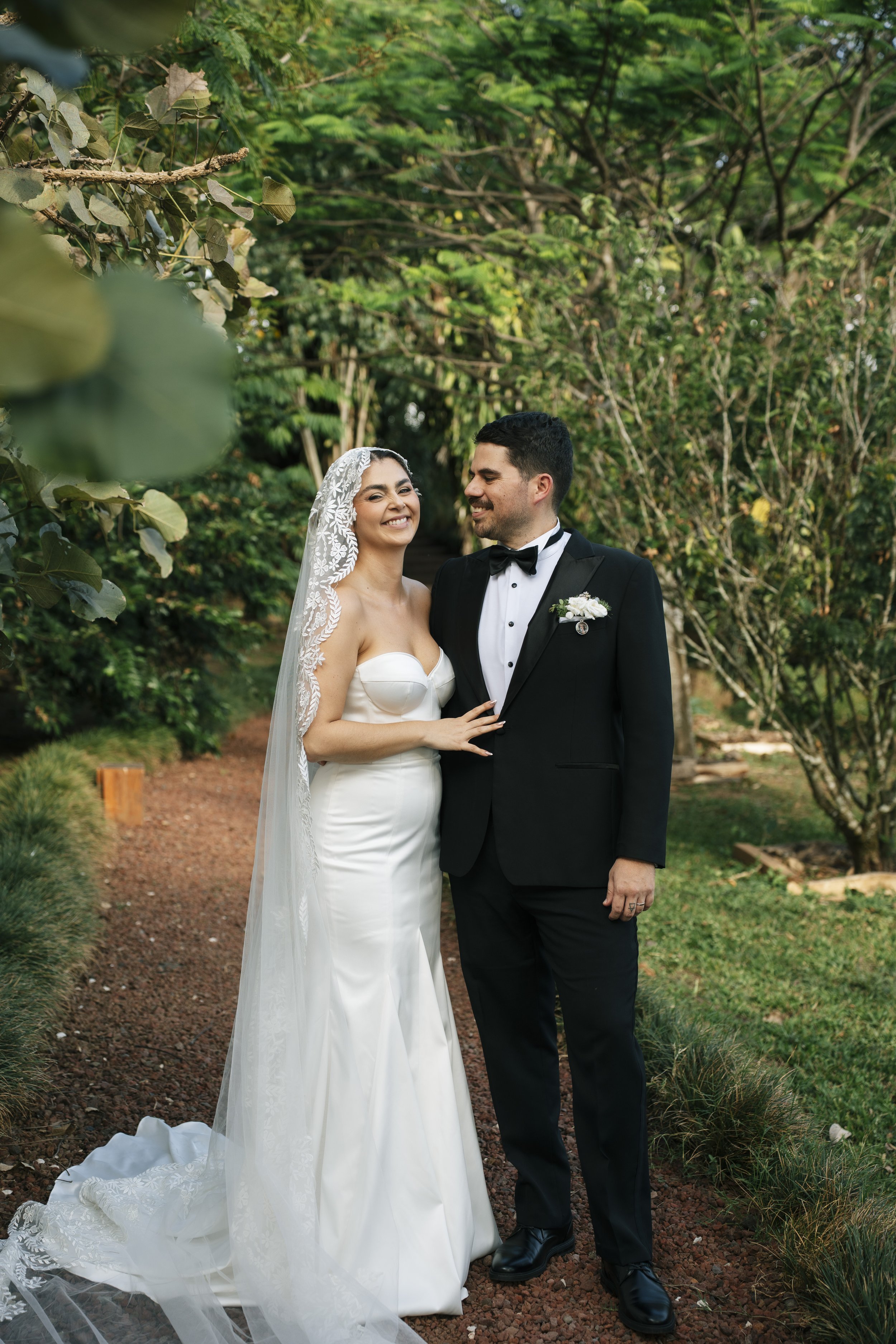Novios recién casados posando al aire libre en un sendero rodeado de árboles y naturaleza durante su boda en Costa Rica.