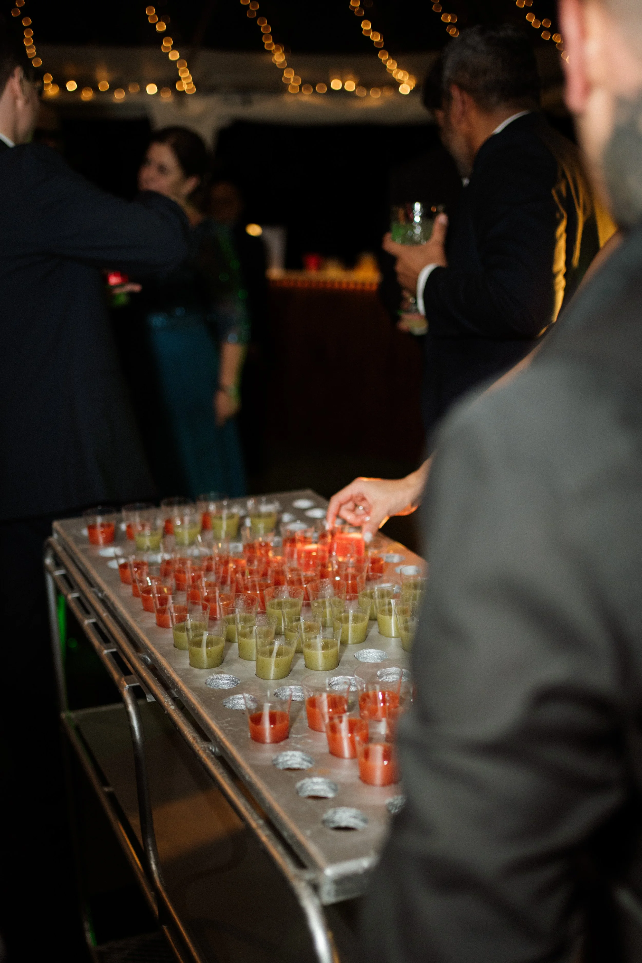 Invitados celebrando alrededor de una mesa con shots de colores durante la fiesta de una boda en Costa Rica.