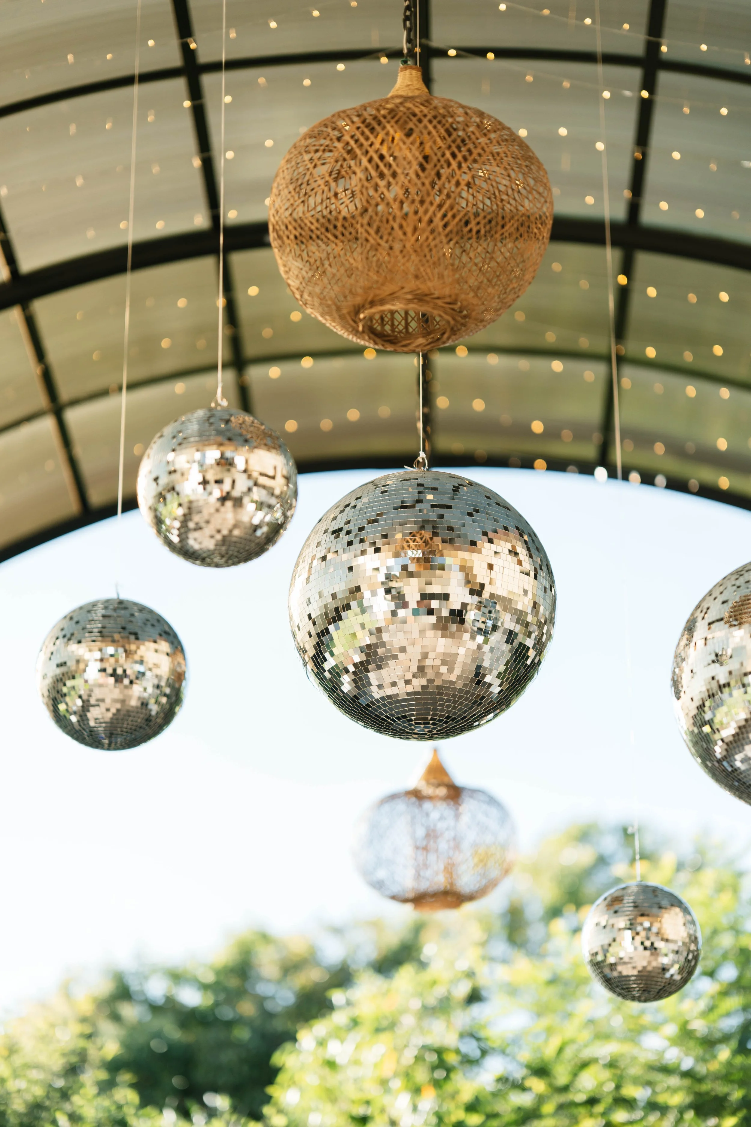 Instalación decorativa al aire libre con bolas disco y lámparas tejidas suspendidas, diseñada para ambientar una boda en Costa Rica.