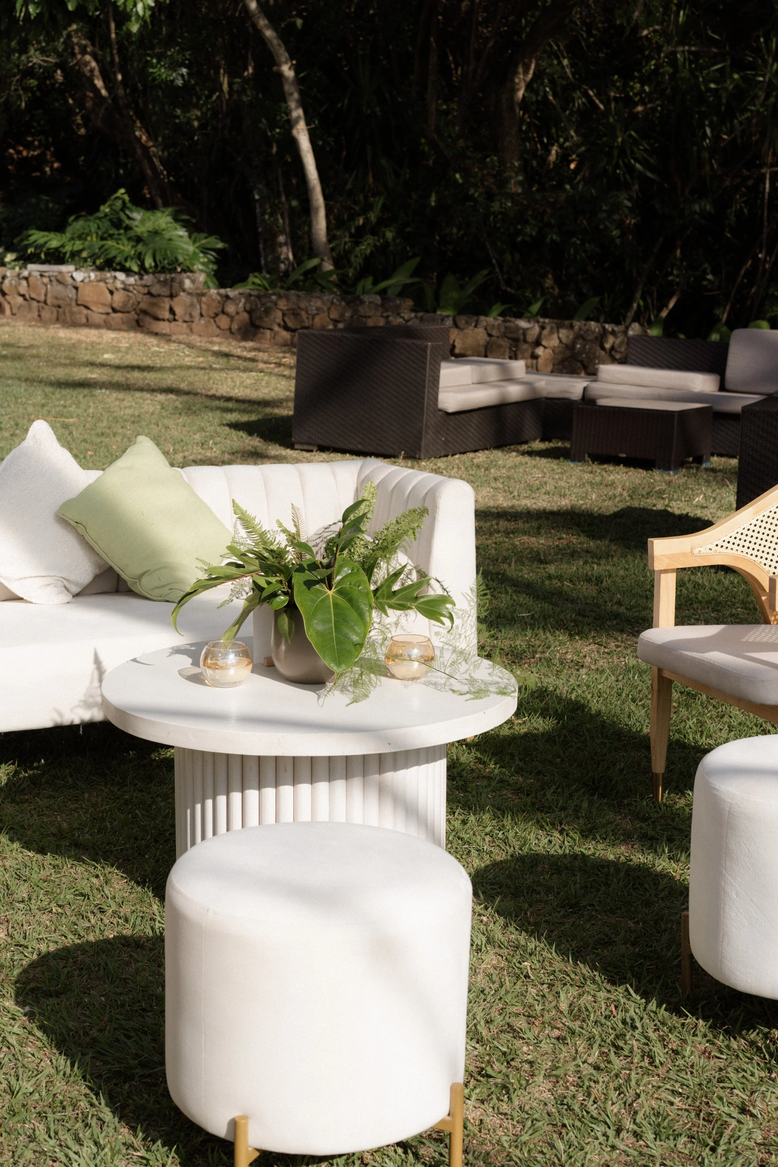 Área lounge al aire libre con sofás, mesa de centro, velas y vegetación alrededor durante una boda en Costa Rica.