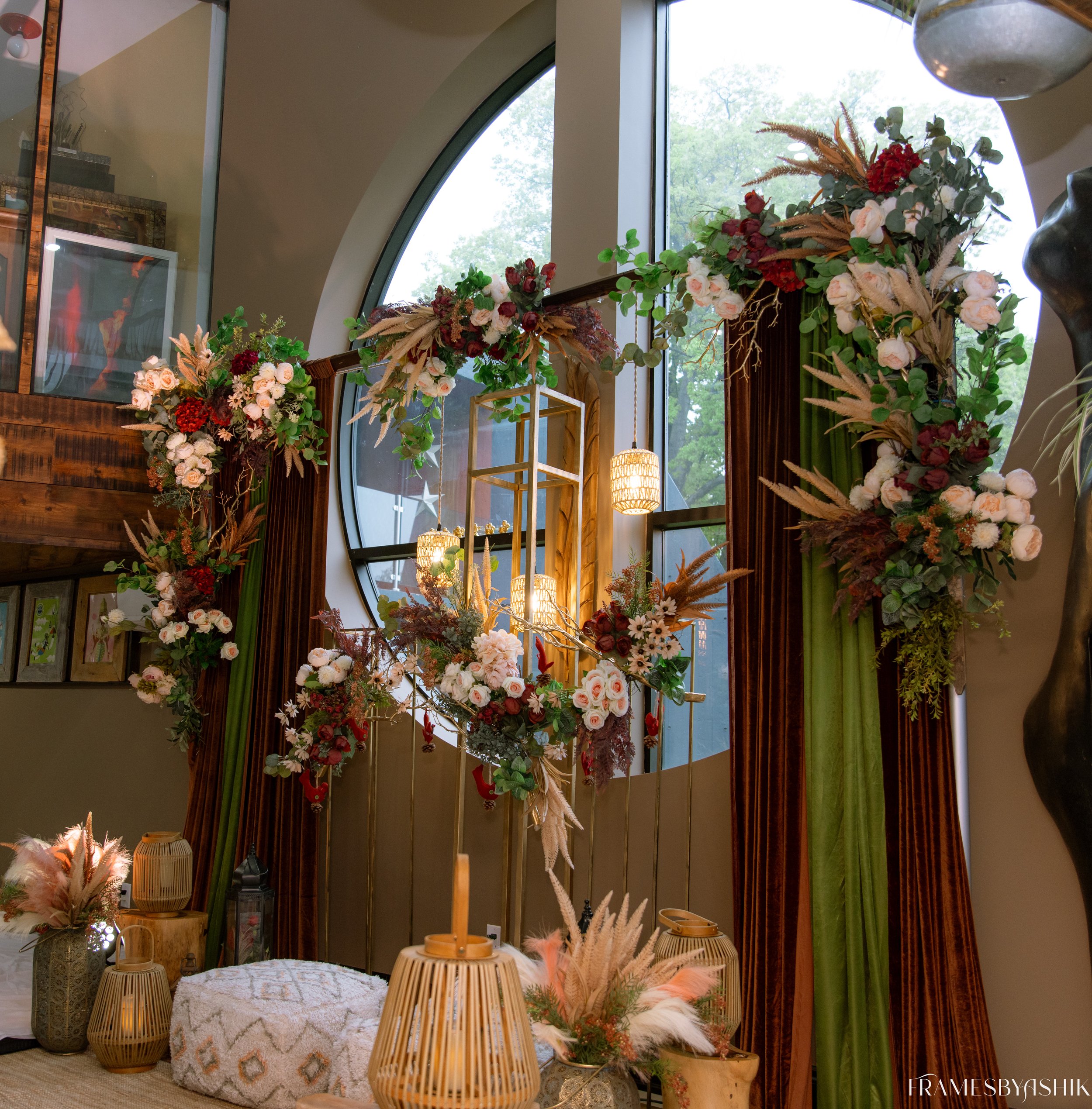 Interior decor with floral arrangement and hanging lights near large arched window.