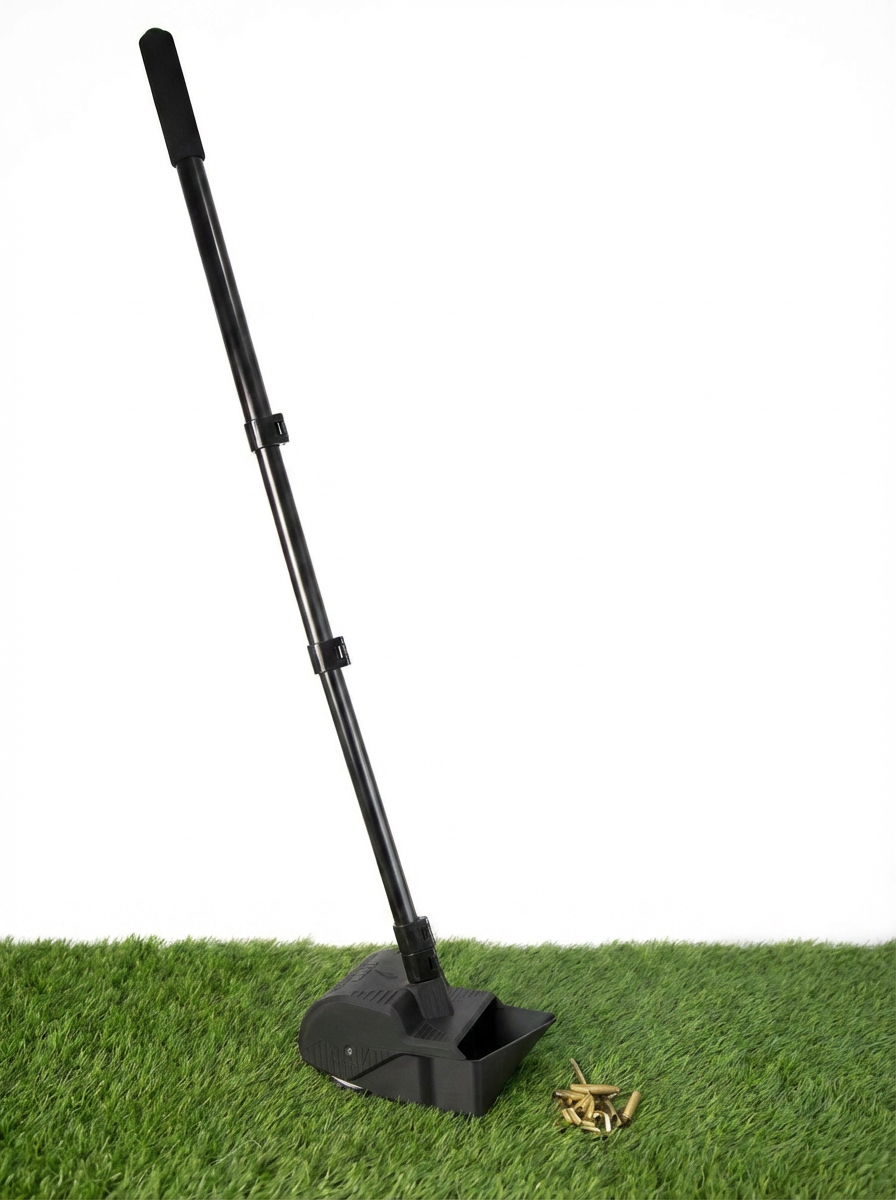 The grass scavenger, a tool used to pick up spent brass cases off grass, sitting on grass with a pile of cases next to it.