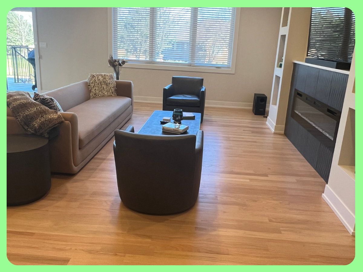 Living room with leather sofa, black armchair, and wooden coffee table, with a fireplace and large window with blinds.