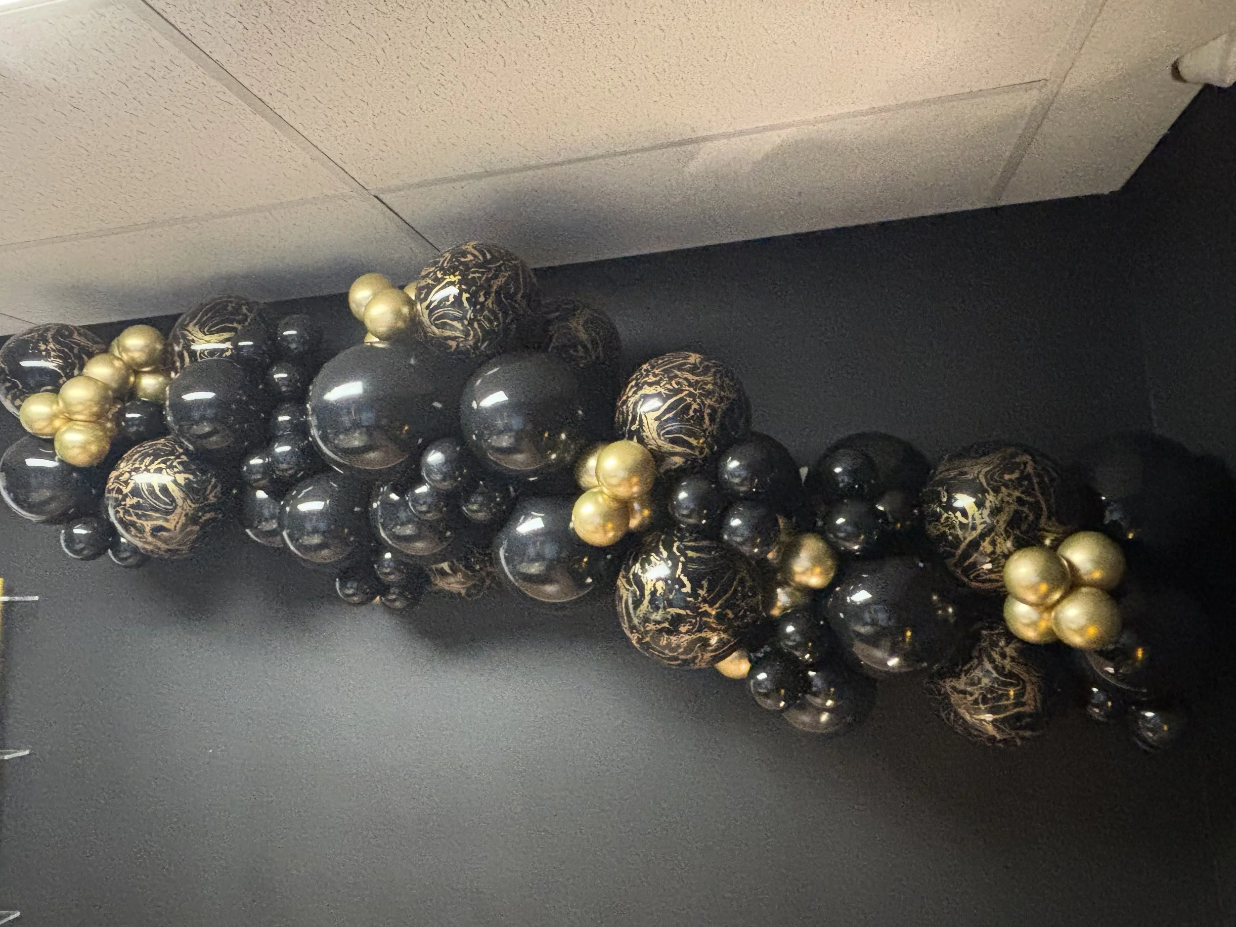 Organic hanging Balloon Arch with black, black with gold marbling, and solid gold balloons.