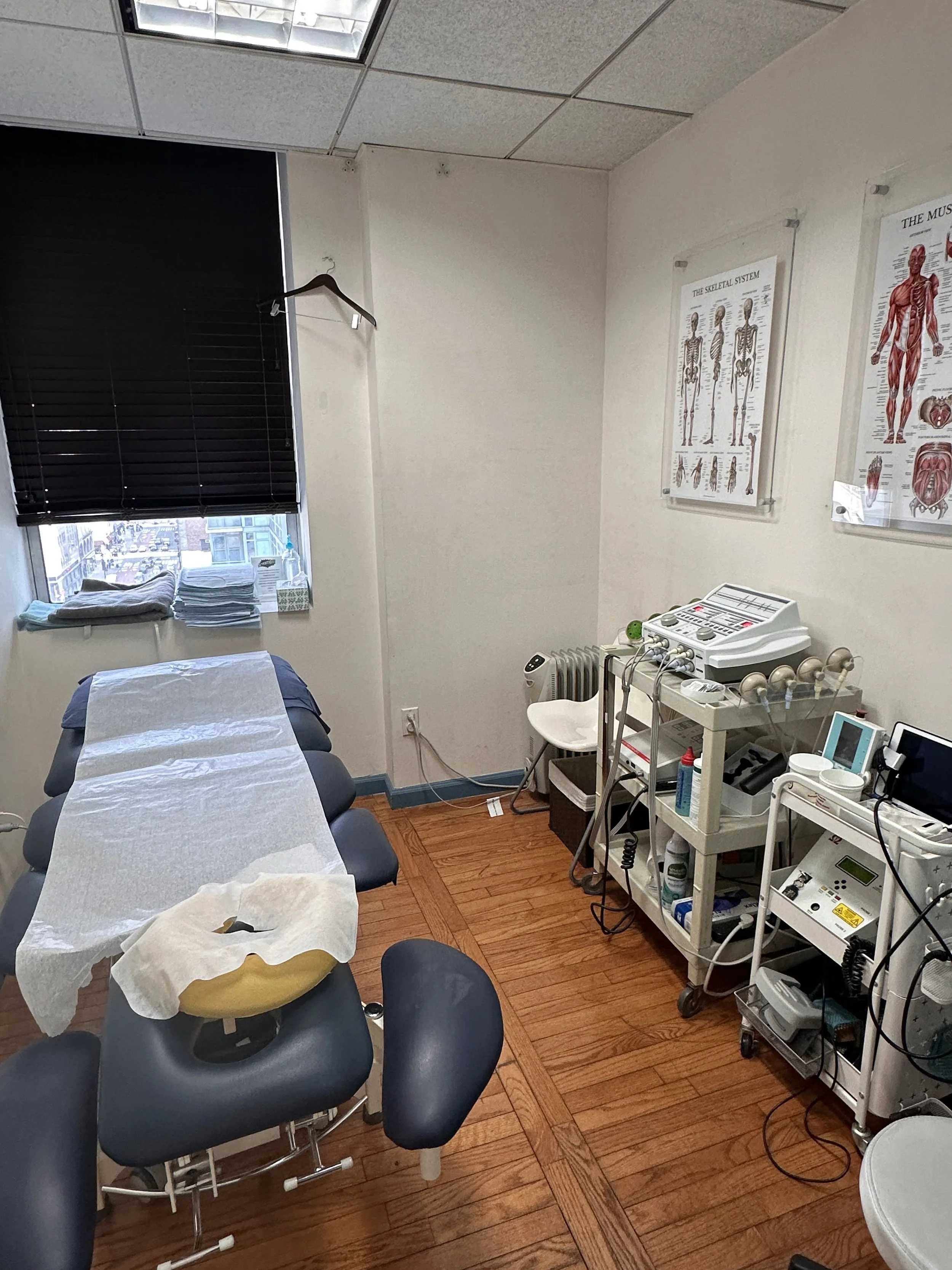 A medical examination room with a bed covered with a paper sheet