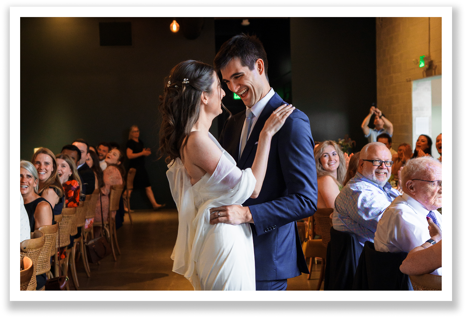 A bride and groom dancing at their wedding reception, surrounded by seated guests who are watching and smiling, who share their wedding testimonial about their experience with wedding Planner Jessica Green of JGreen Weddings.