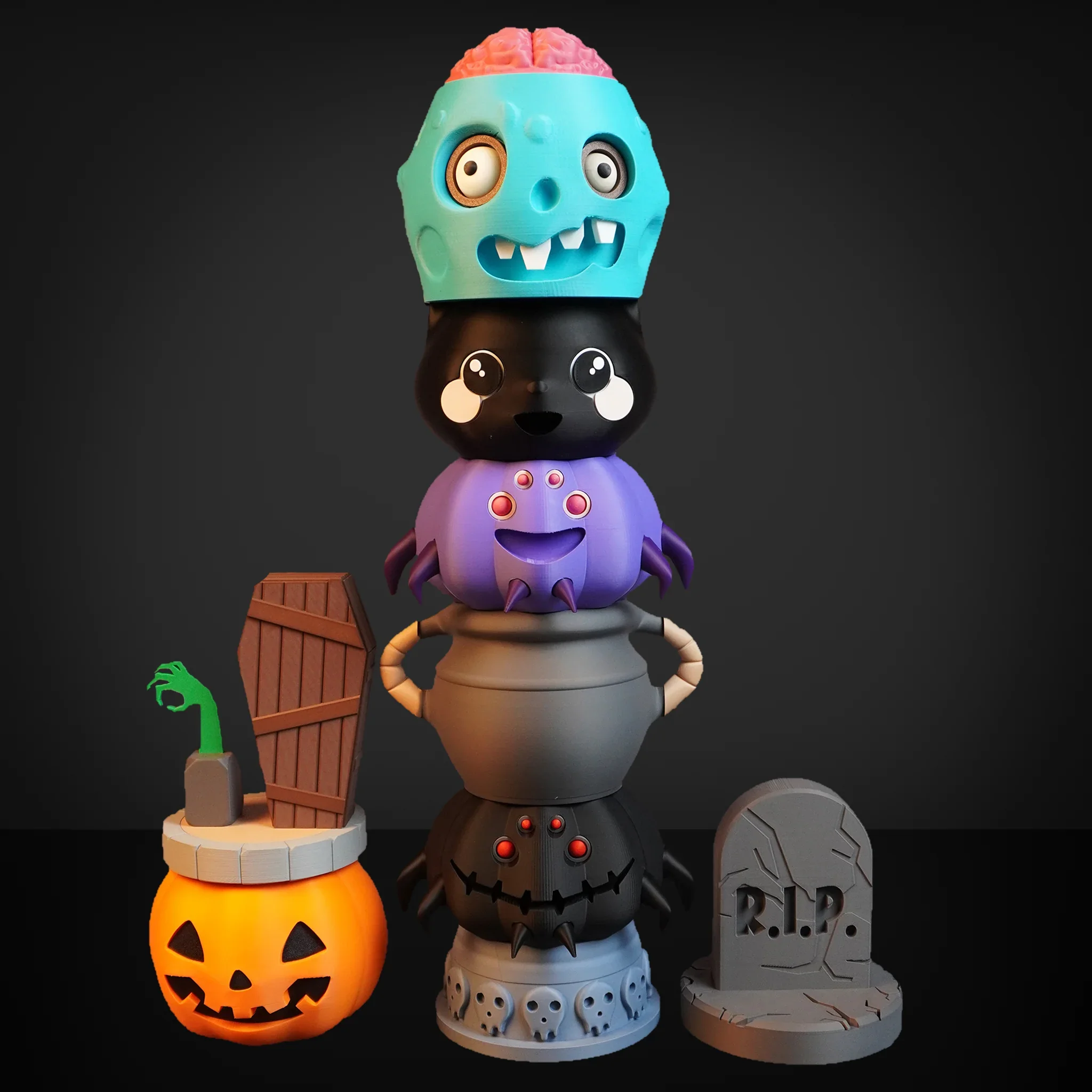 Various Halloween-themed 3D-printed objects including a pumpkin, a black cat, a skull, a monster face, and a pumpkin bunting, against a black background.