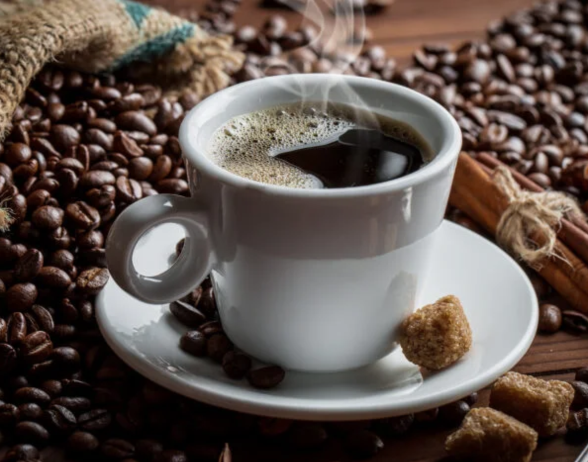 Premium Colombian coffee presented in a classic white cup, surrounded by roasted coffee beans, cinnamon sticks, and sugar cubes. This image highlights the rich aroma, quality, and export value of Colombian coffee.