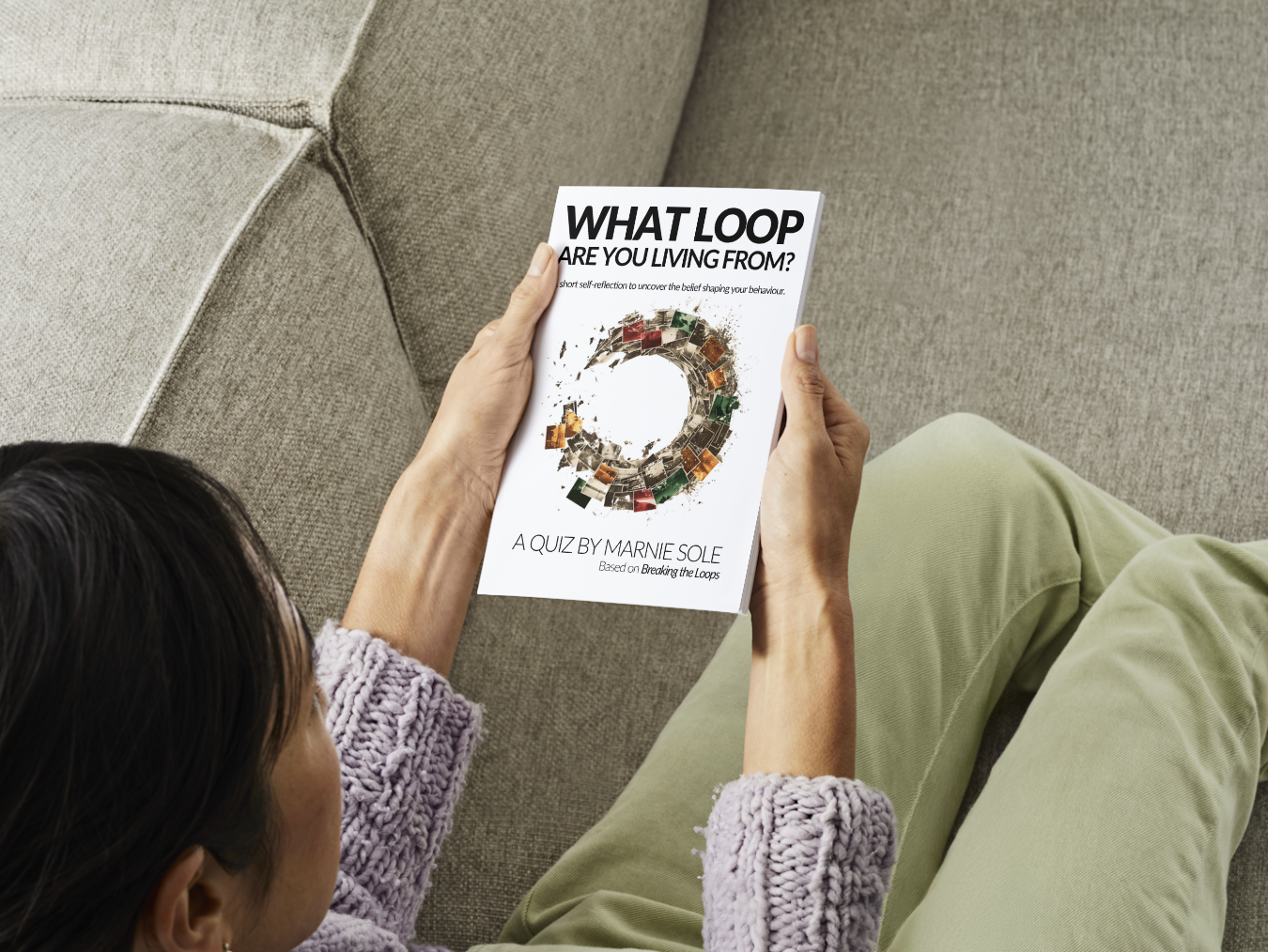 Person sitting on a beige couch holding a magazine titled 'What Loop Are You Living From?' with a circular design on the cover.