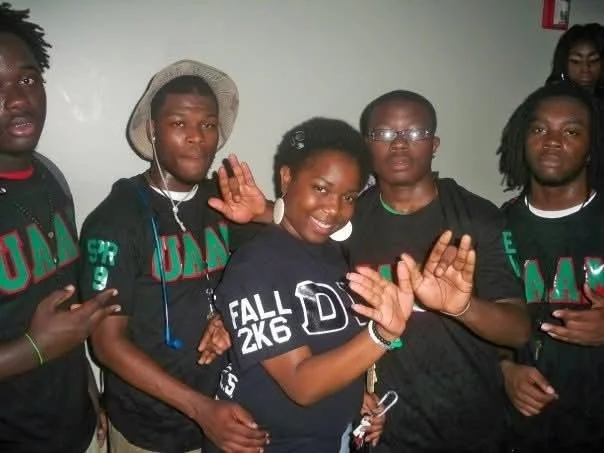 Group of five young people posing together, some making peace signs, in casual clothing.