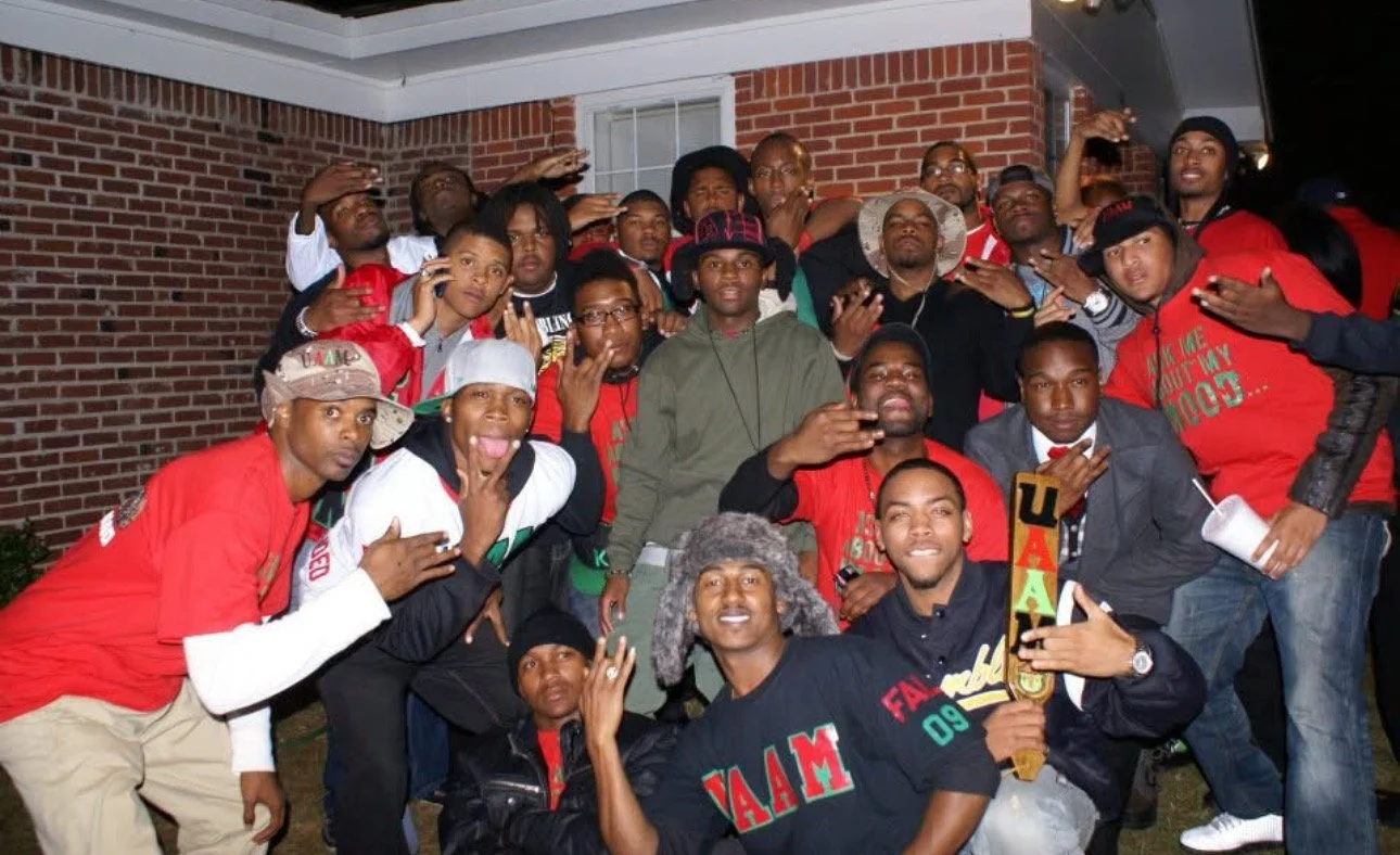 Group of people gathered outdoors at night, posing for a photo in front of a brick building.
