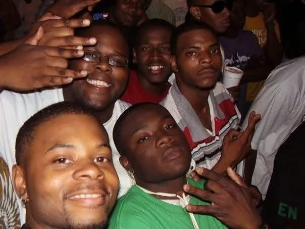 Group of men taking a selfie together at a crowded event.